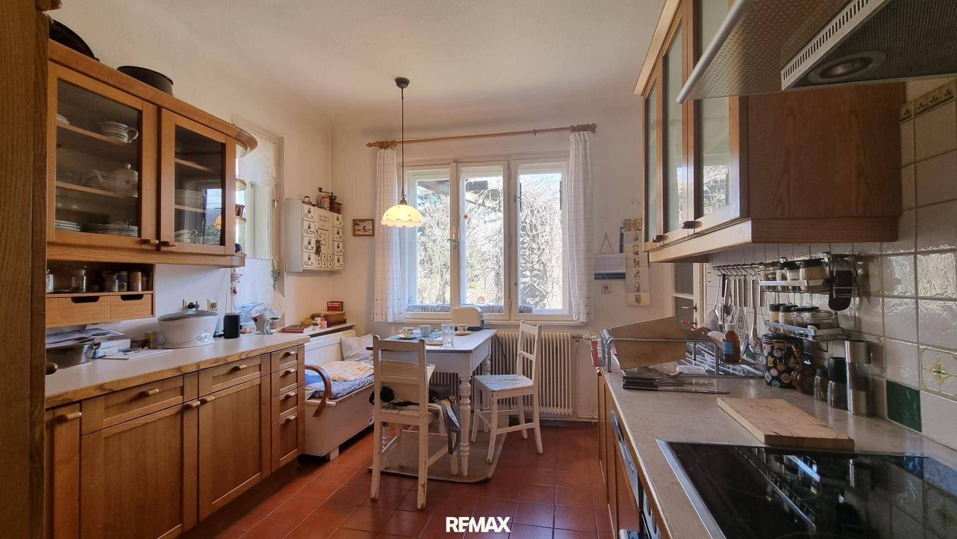 Traditionelle Küche mit Holzeinbauten, Essbereich am Fenster und Terrakottafliesen.