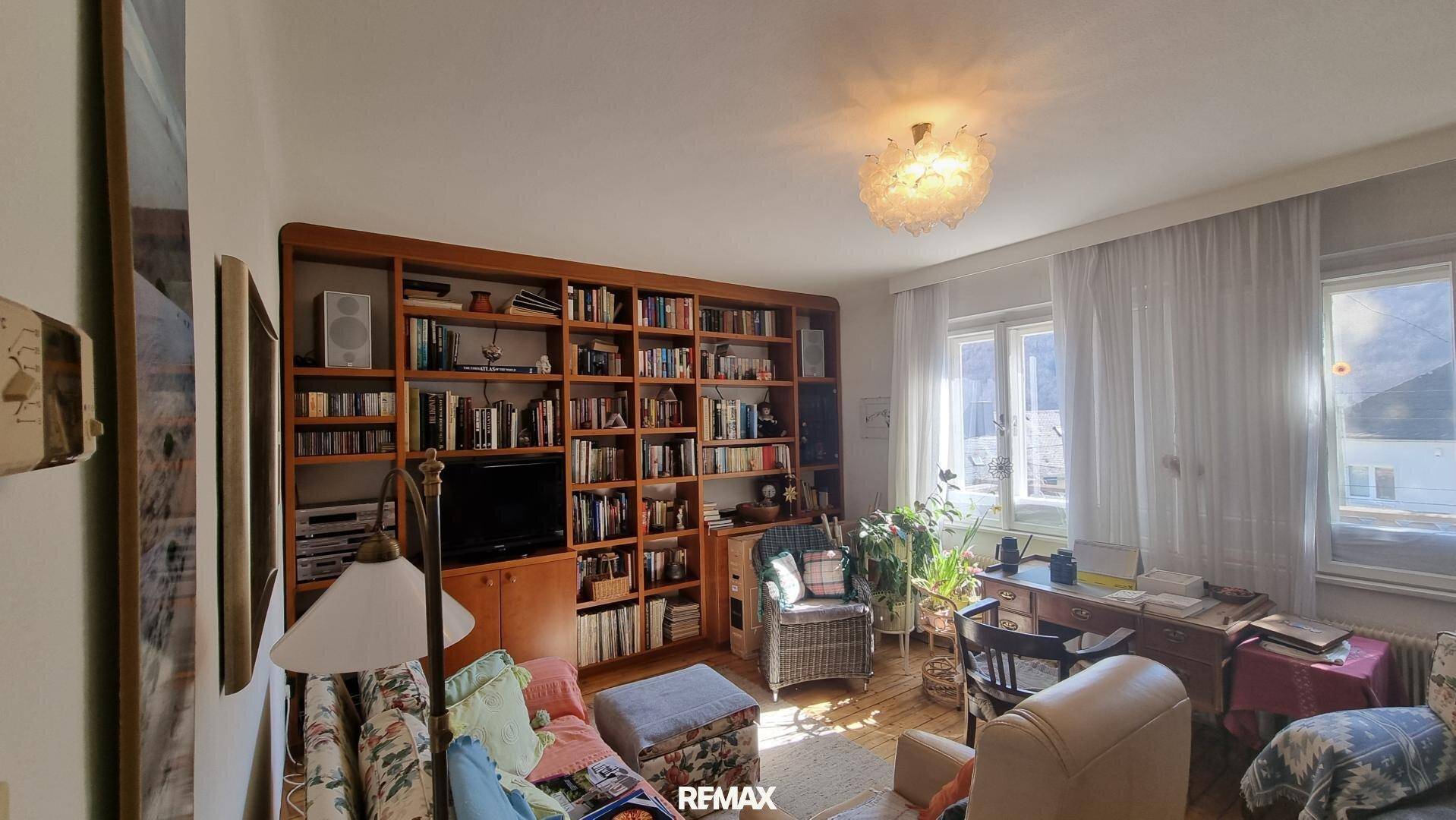 Gemütliches Wohnzimmer mit großer Bücherwand, vielen Büchern und natürlichem Lichteinfall.