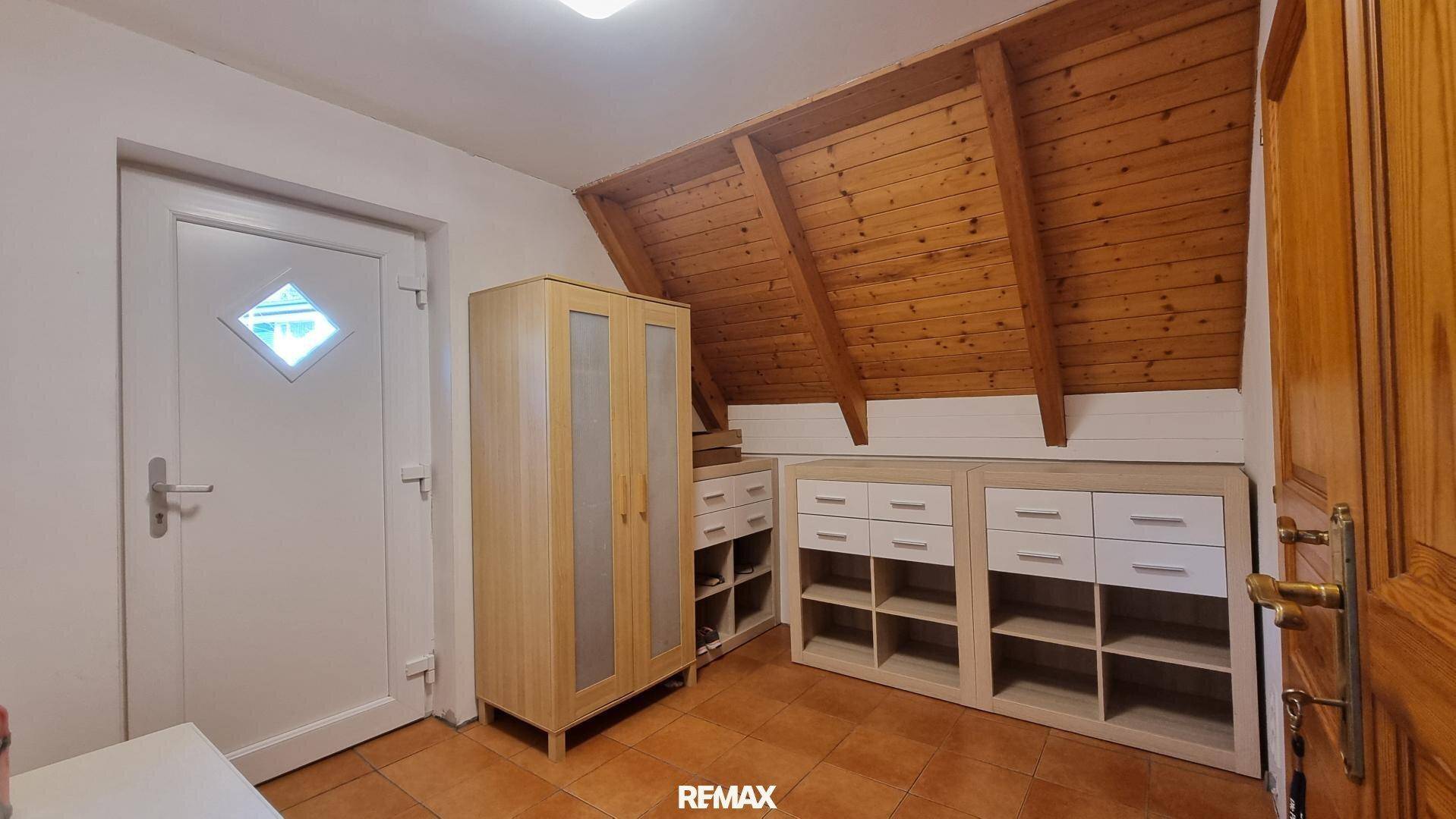 Dachzimmer mit Holzverkleidung, Dachschräge und Stauraum, hell und funktional.