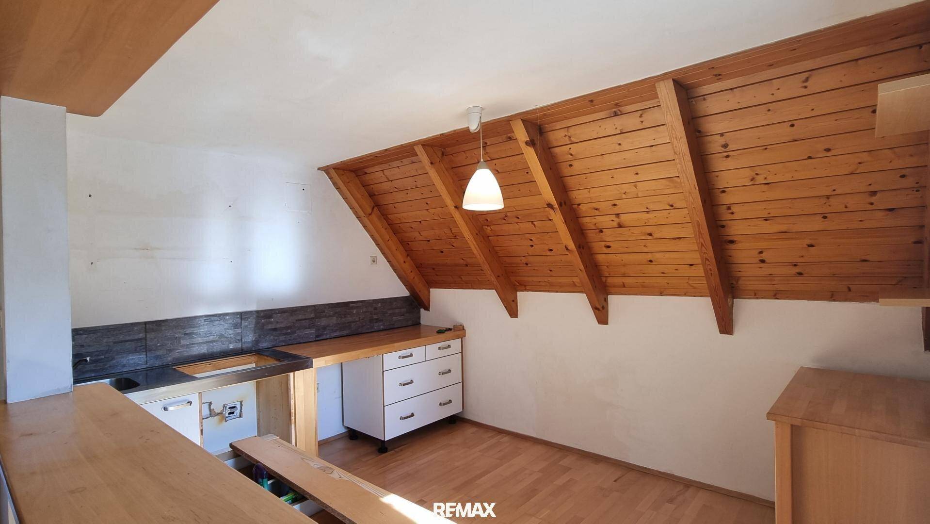 Kleine Küchenzeile im Dachgeschoss mit Holztheke und Stauraum unter der Dachschräge.