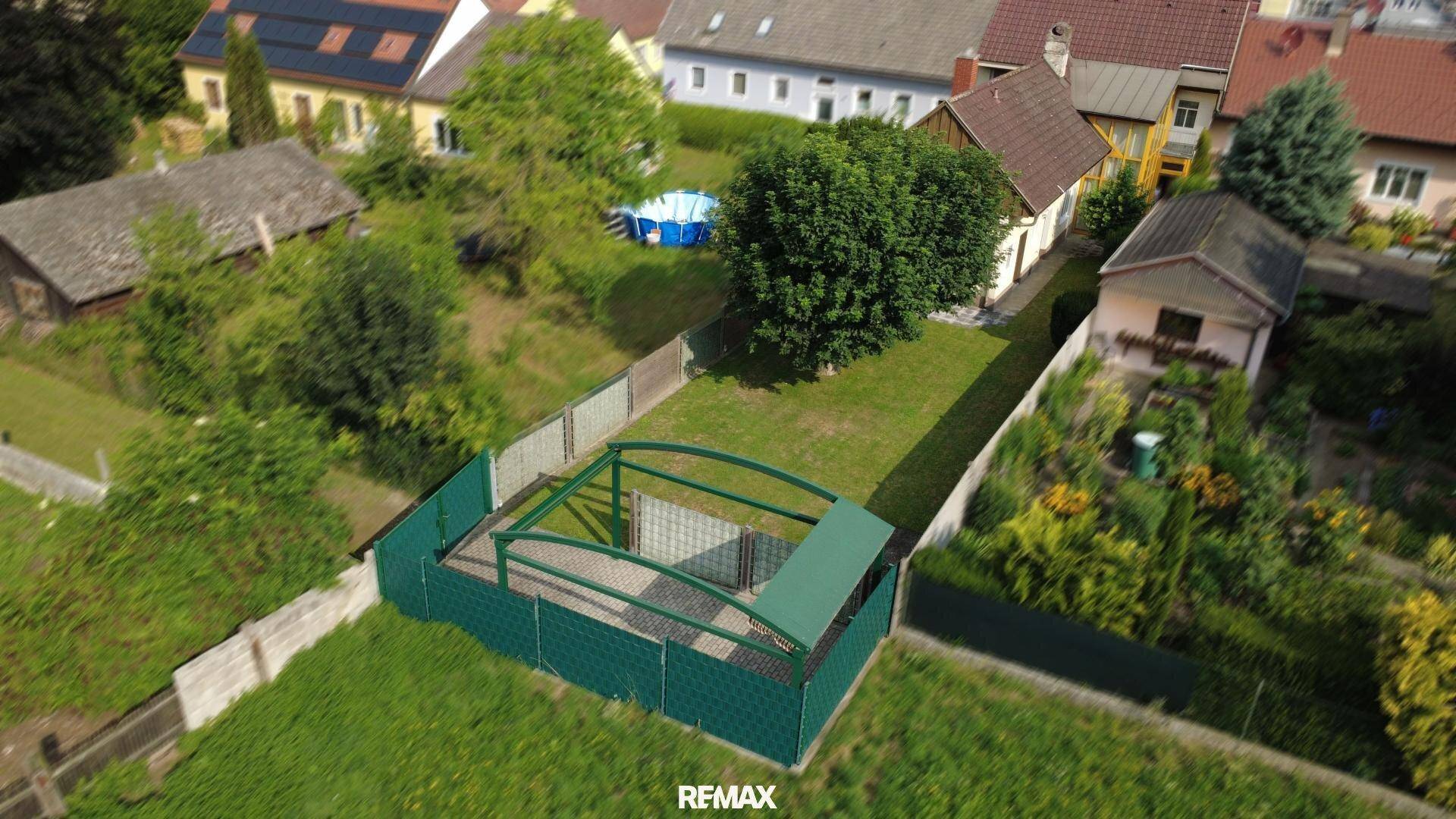 Luftaufnahme des Grundstücks mit Garten, Carport und angrenzenden Häusern.