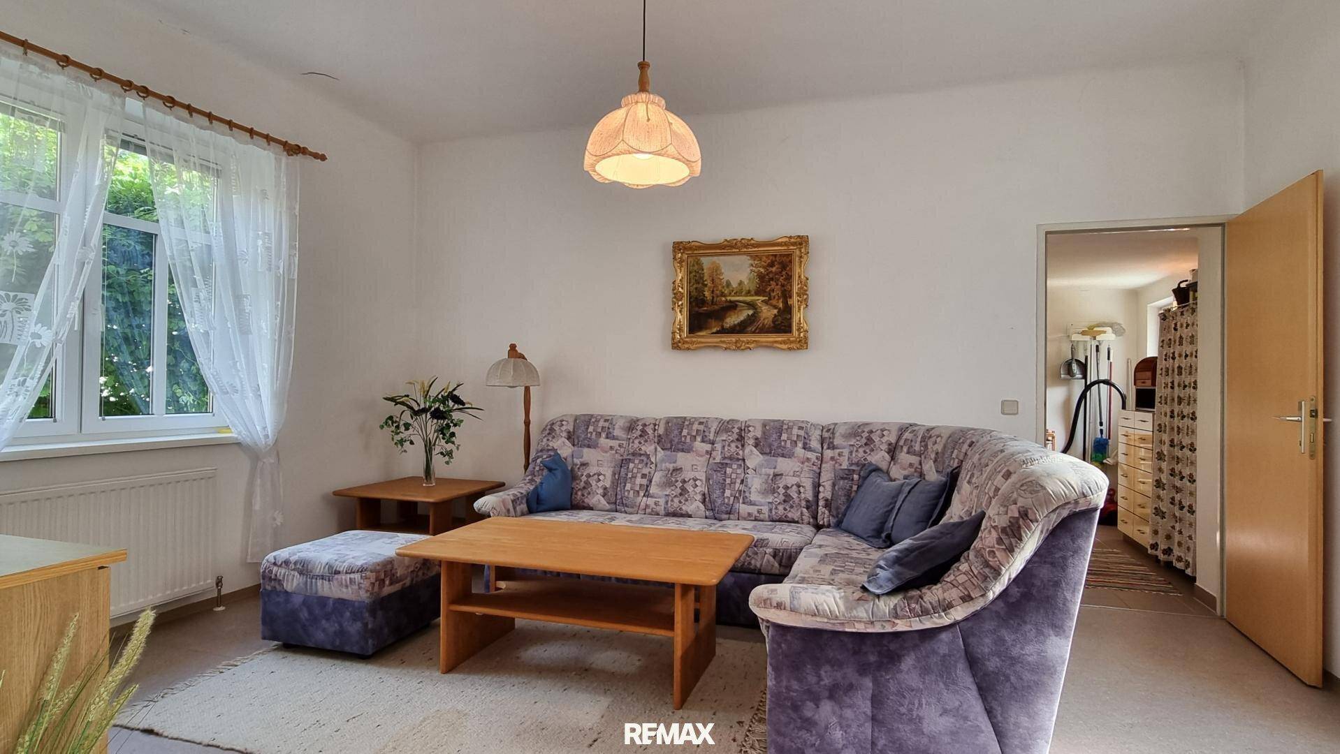 Gemütliches Wohnzimmer mit Sofa, Couchtisch und großem Fenster für viel Tageslicht.