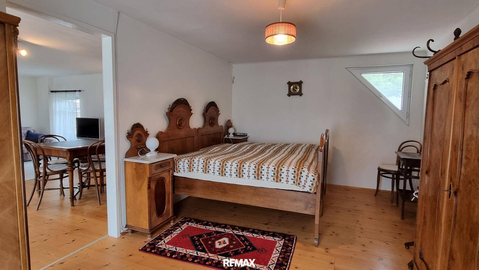 Schlafzimmer mit Doppelbett, Holzmöbeln und Zugang zum Wohnbereich.