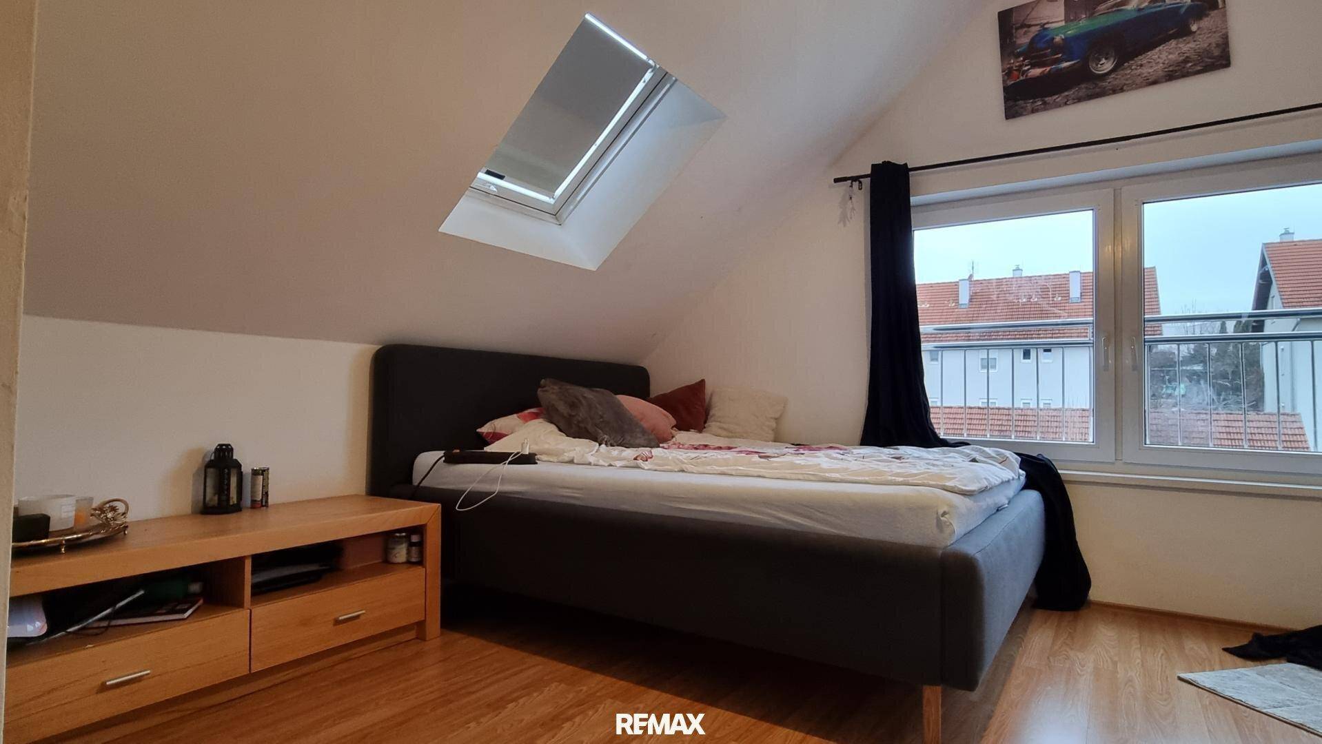 Gemütliches Schlafzimmer im Dachgeschoss mit Bett, Fenster und Dachfenster, das viel Licht spendet.
