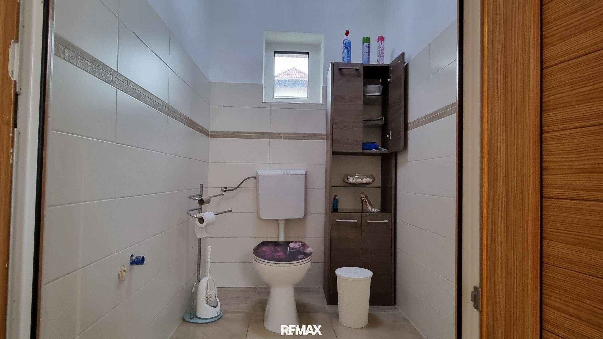 Separate Toilette mit WC, kleinem Fenster und einem praktischen Wandschrank.
