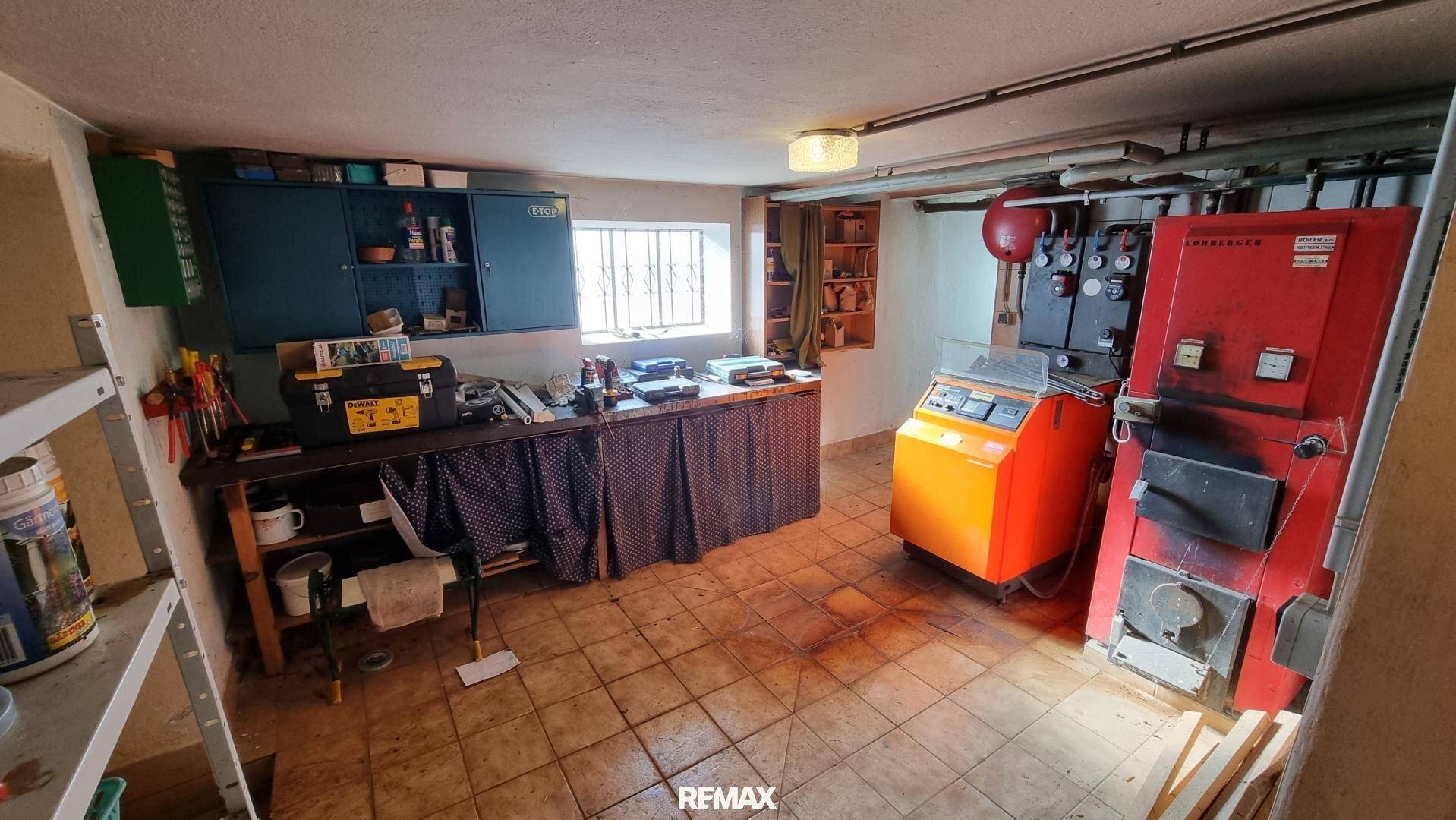 Heizraum im Keller mit Ölheizung und Werkbank, funktional eingerichtet und gefliest.