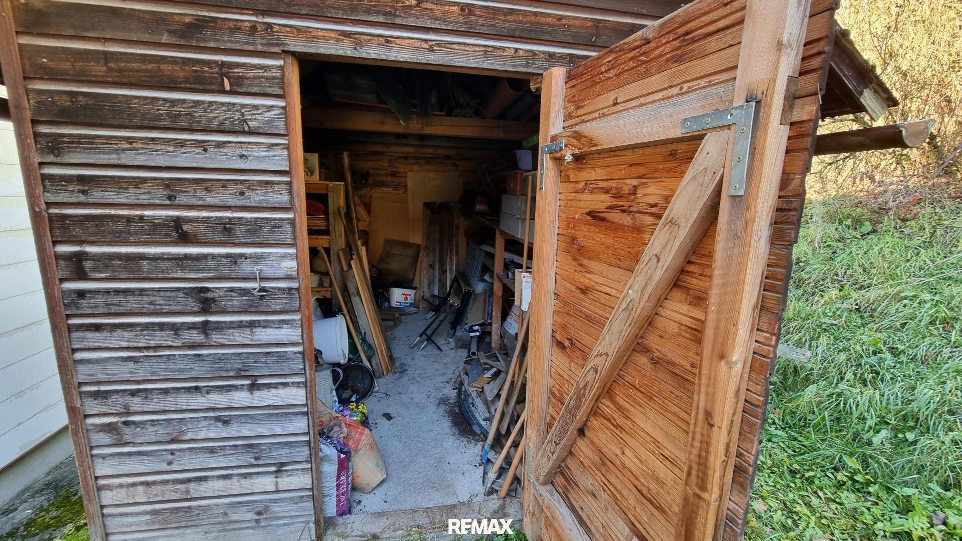 Innenansicht eines Holzschuppens, gefüllt mit Werkzeugen und verschiedenen Gegenständen.