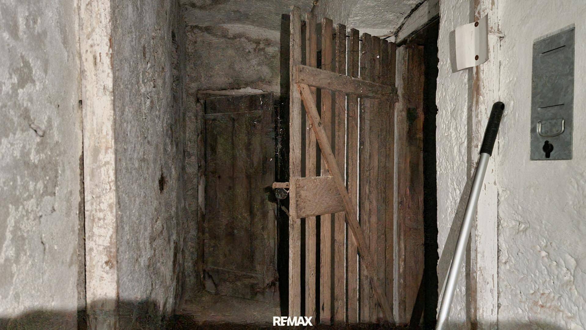 Kellerraum mit Holztüren und rauen Wänden, der als Lagerfläche dient und viel Stauraum bietet.