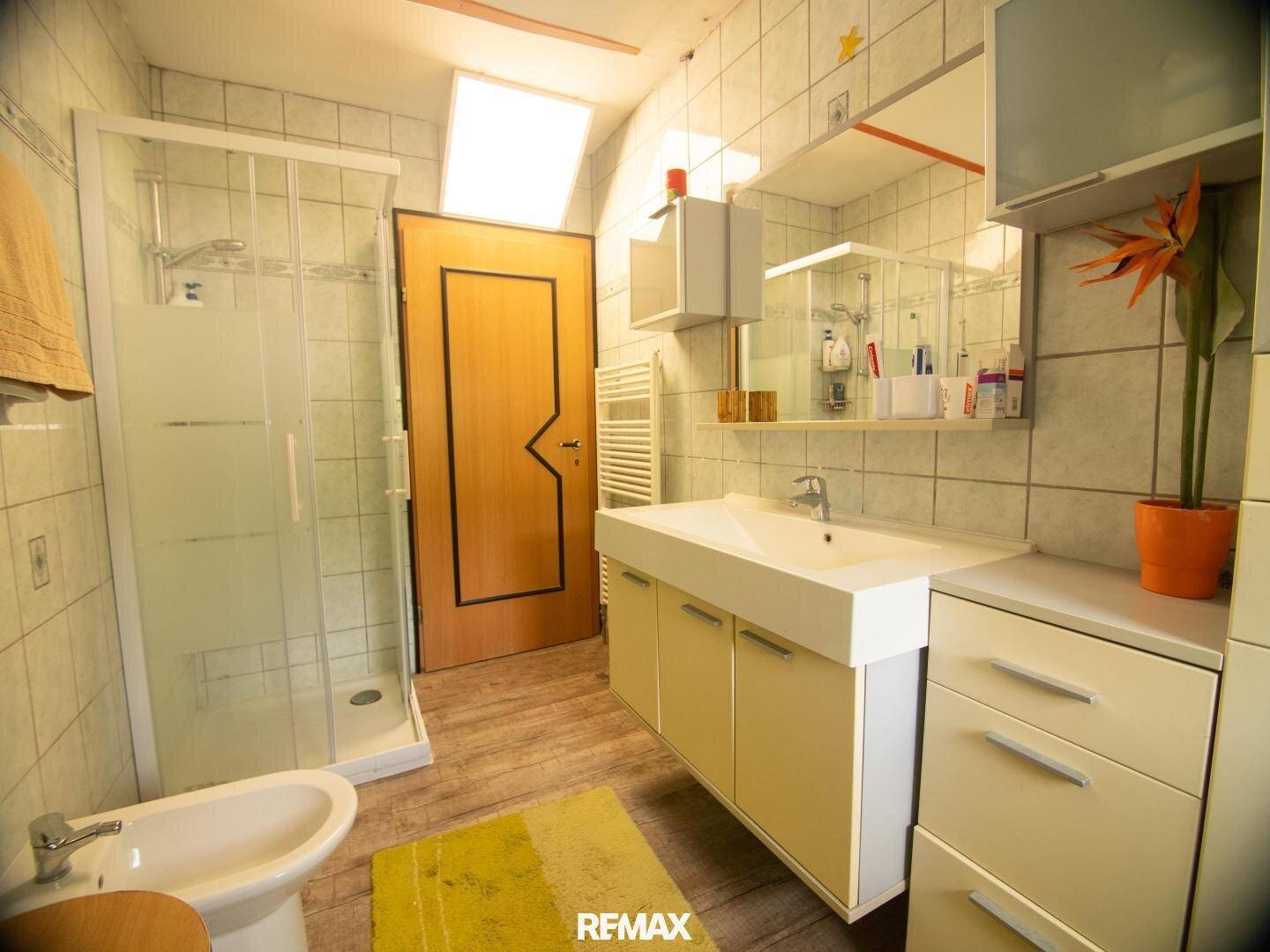 Badezimmer mit Dusche, Bidet, Waschtisch und Dachfenster.