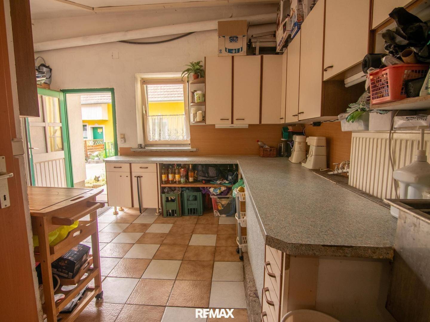 Geräumige Küche mit viel Arbeitsfläche, Stauraum und Blick ins Grüne durch das Fenster.