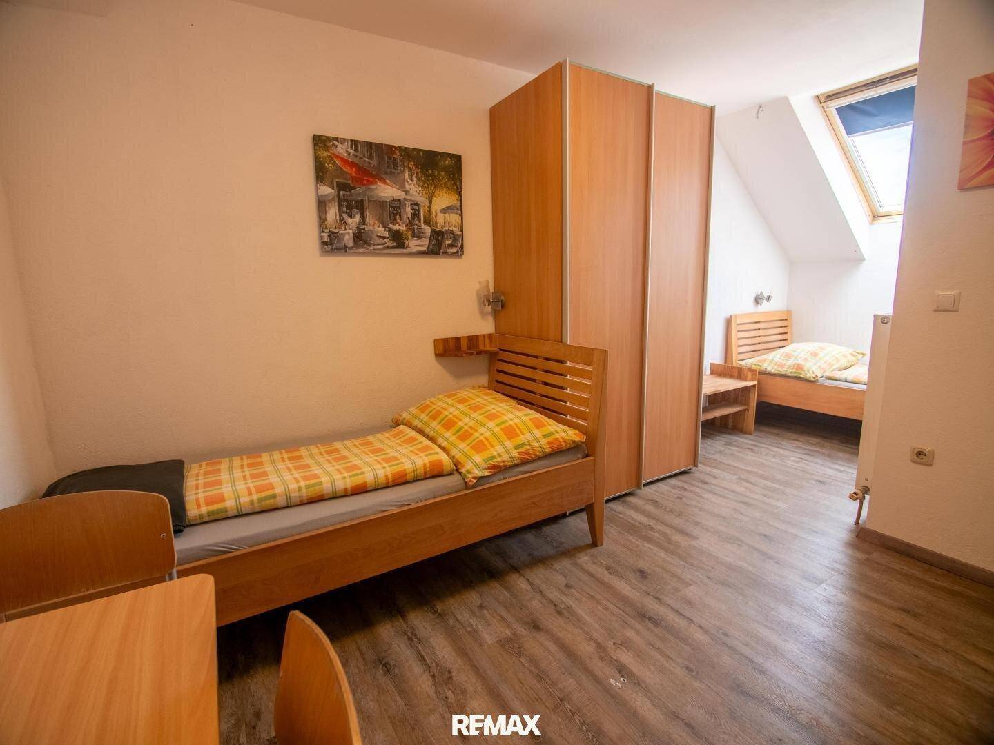 Schlafzimmer mit zwei Betten, Holzboden und Holzschränken.