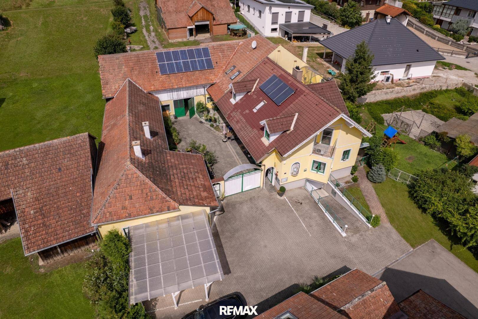 Luftaufnahme des Anwesens mit mehreren Gebäuden, Photovoltaikanlagen und großzügigen Außenbereichen.