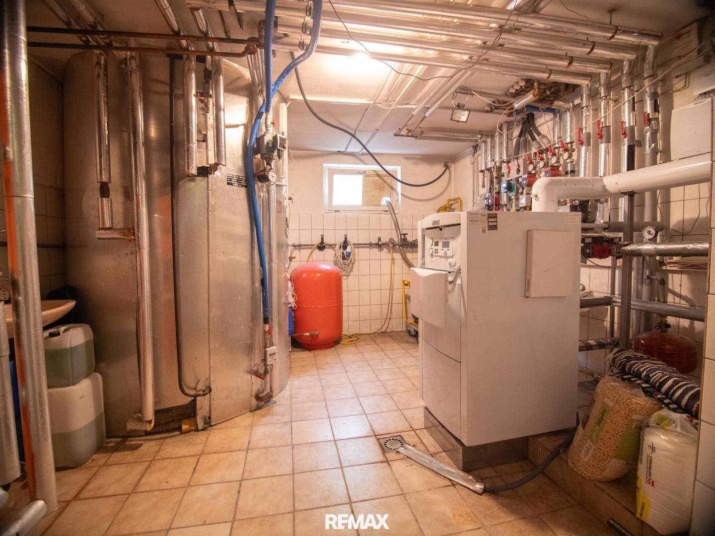 Heizungsraum mit großen Warmwasserspeichern und komplexer Rohrleitungsinstallation, funktional und gut gewartet.