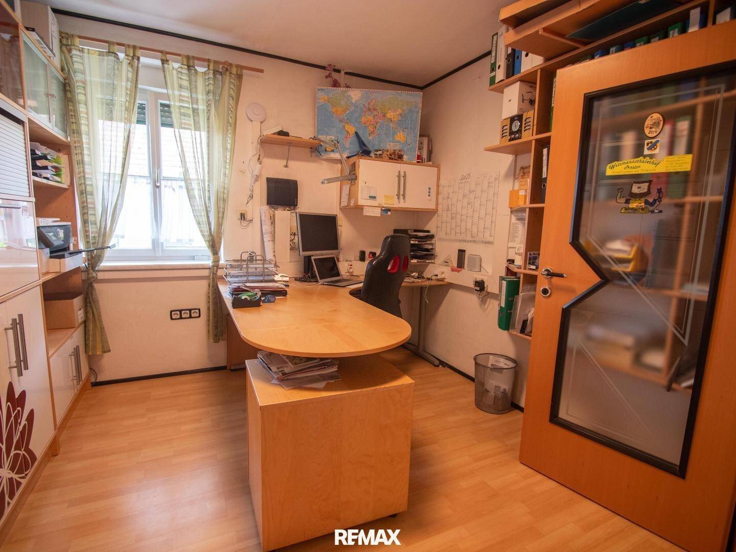 Funktionales Heimbüro mit Holzmöbeln, Schreibtisch und vielen Regalen.
