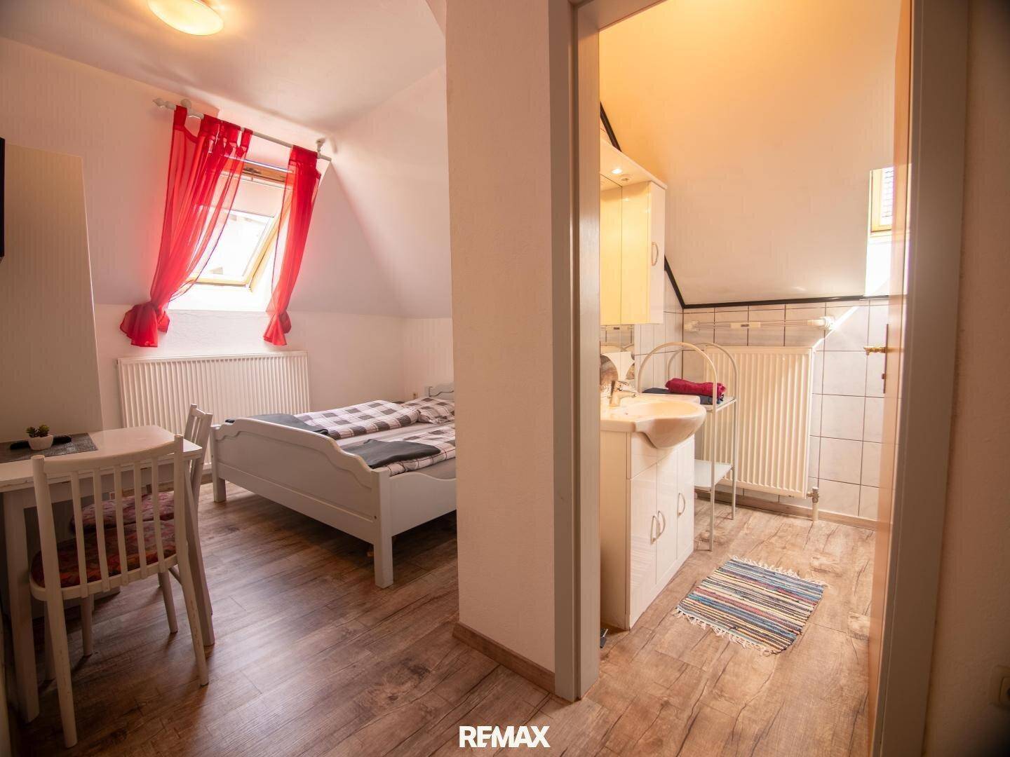 Schlafzimmer im Dachgeschoss mit Bett, Waschbecken und Dachschräge.