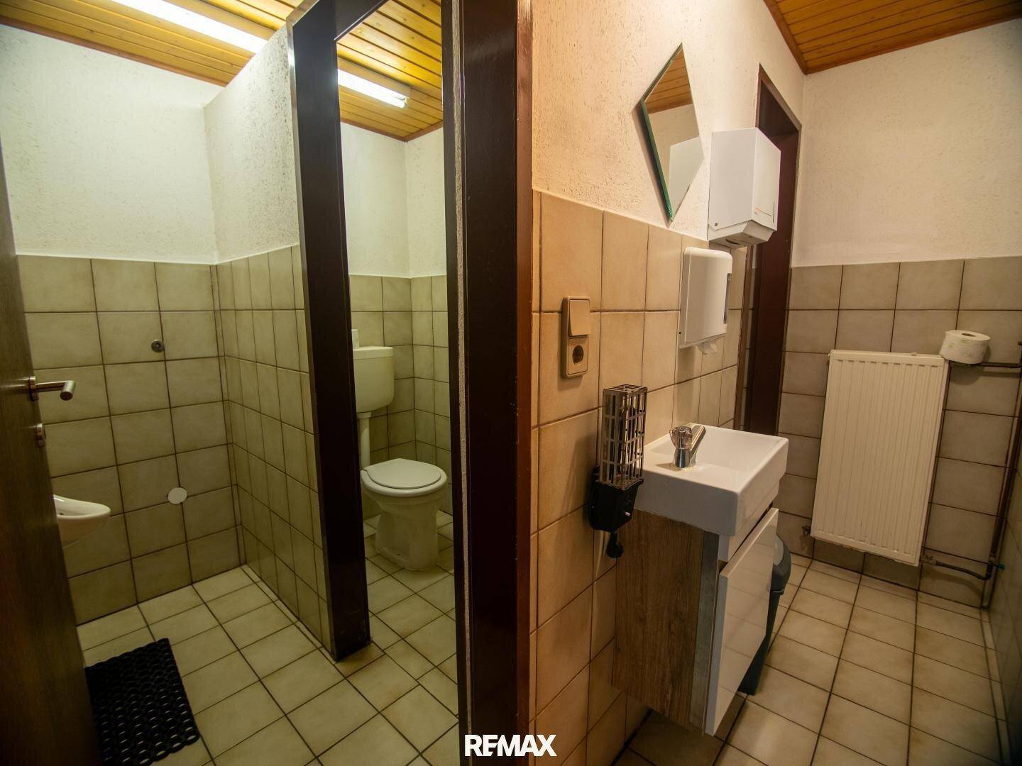 Einfaches Gäste-WC mit Fliesen an Wänden und Boden, ausgestattet mit Waschbecken und Toilette.