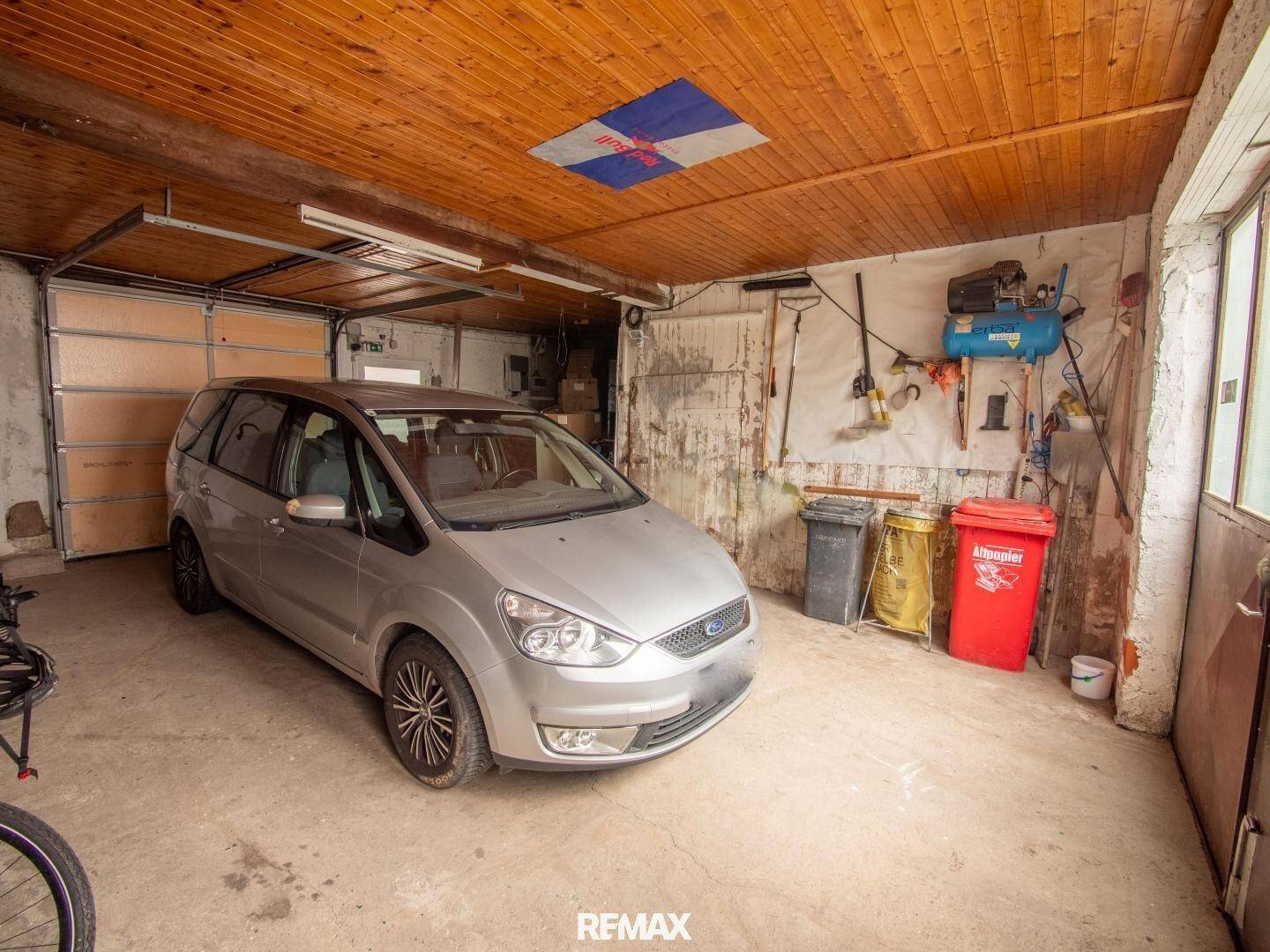 Geräumige Garage mit einem geparkten Auto, Stauraum und direktem Zugang nach draußen.