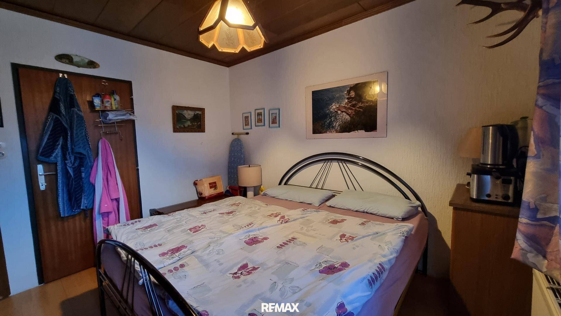 Gemütliches Schlafzimmer mit Metallbettgestell, Holztäfelung an der Decke und traditioneller Einrichtung.