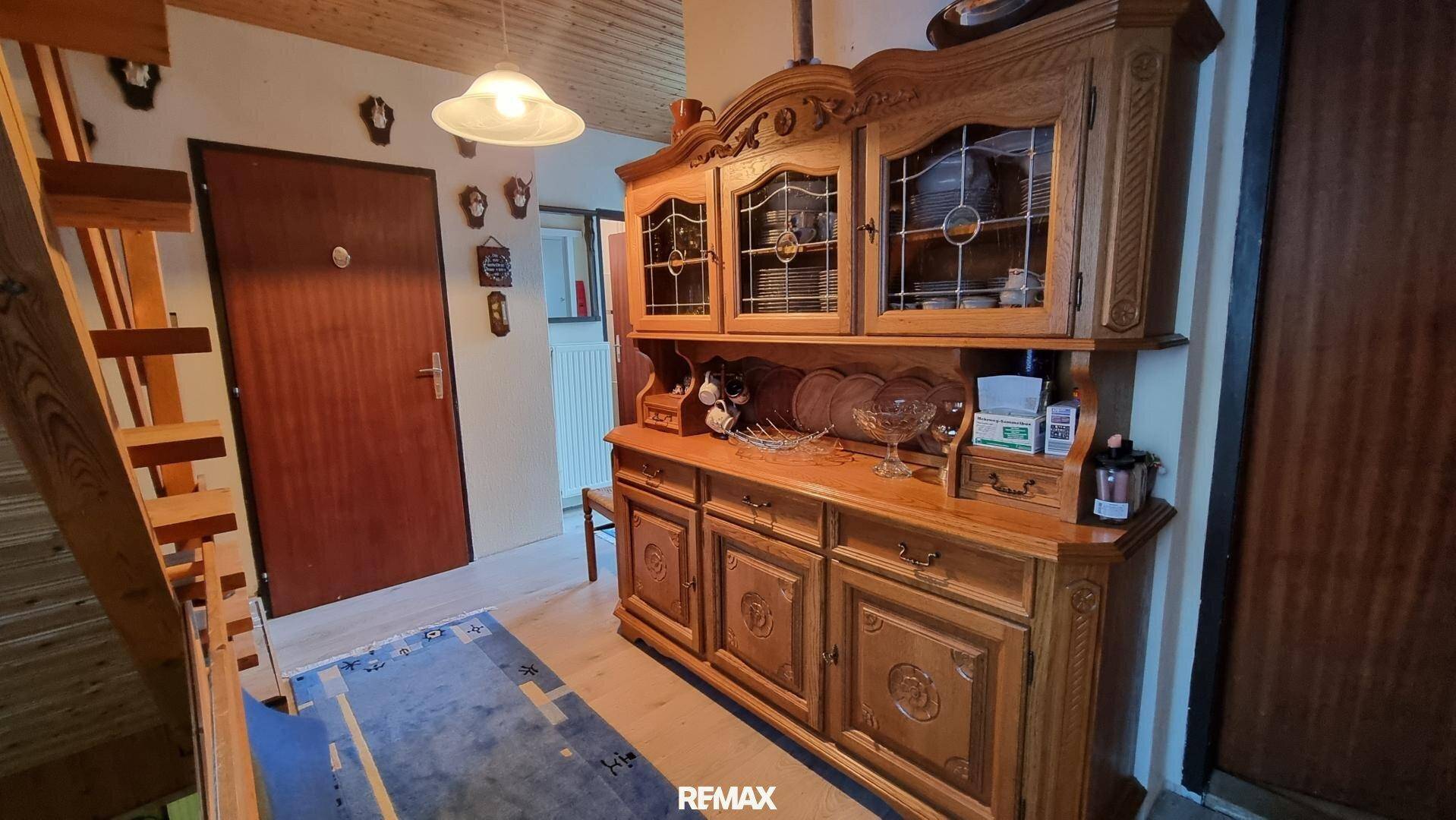 Flur mit rustikalem Holzschrank, Treppe und traditioneller Dekoration.