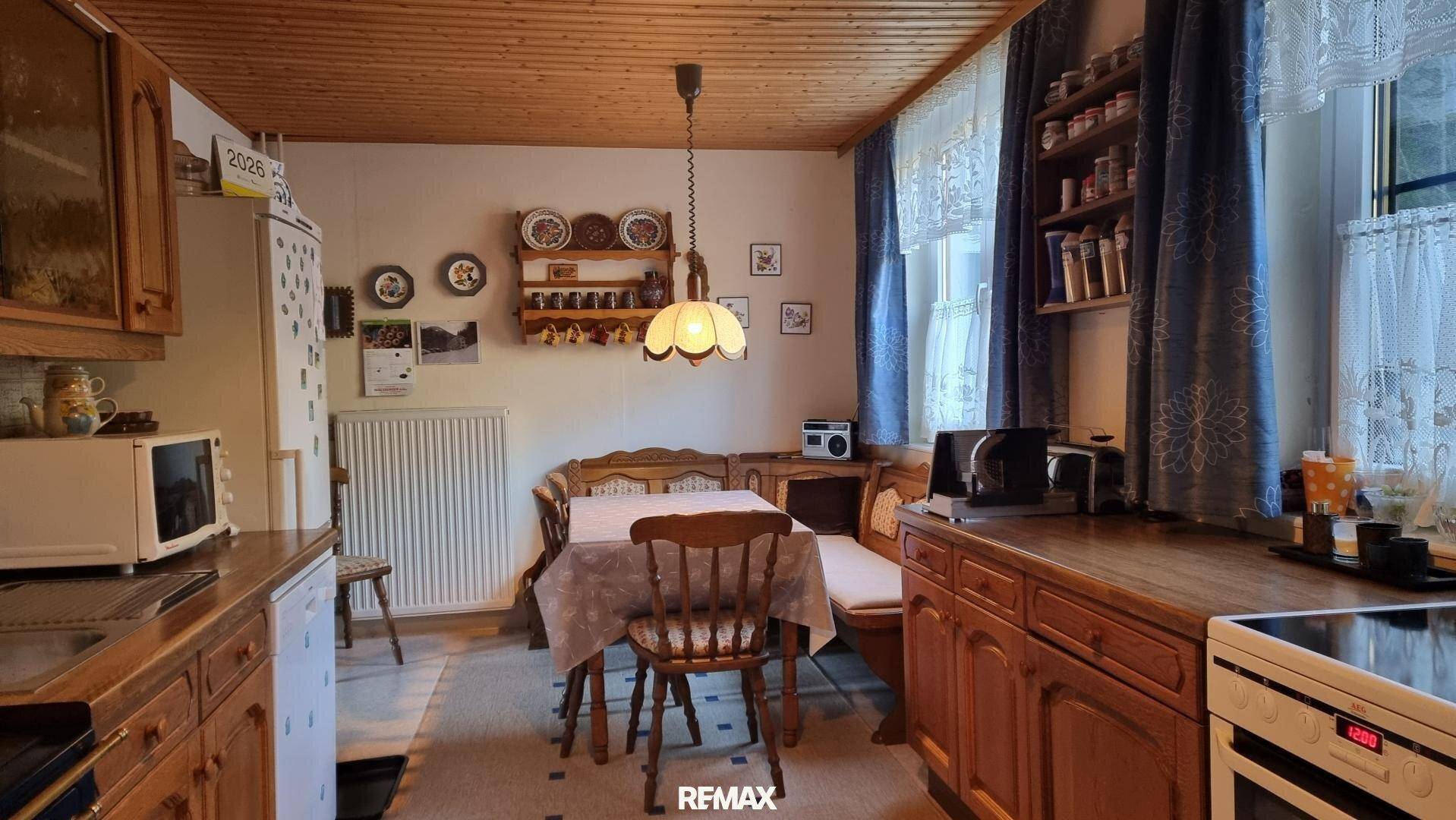 Gemütliche Wohnküche im Landhausstil mit Holztäfelung, Essecke und traditionellen Möbeln.