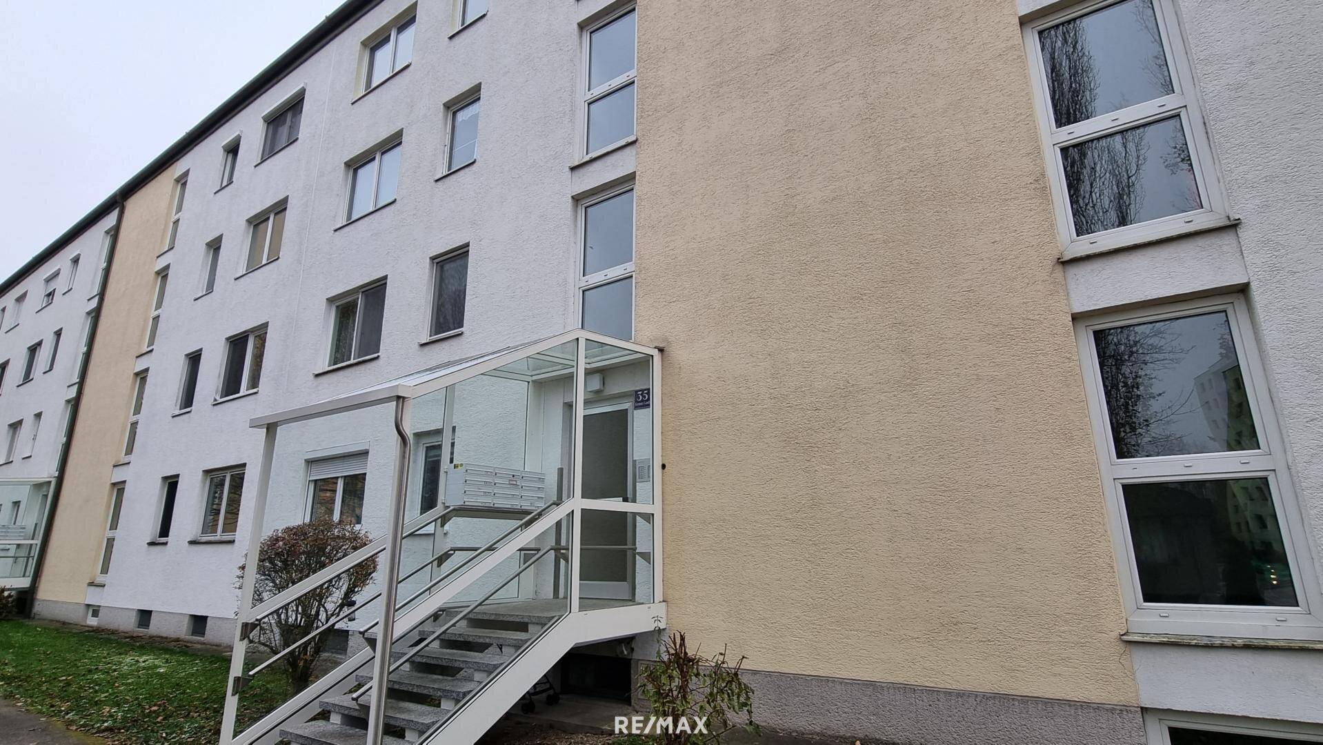 Mehrfamilienhaus mit modernisiertem Eingangsbereich und großen Fenstern.