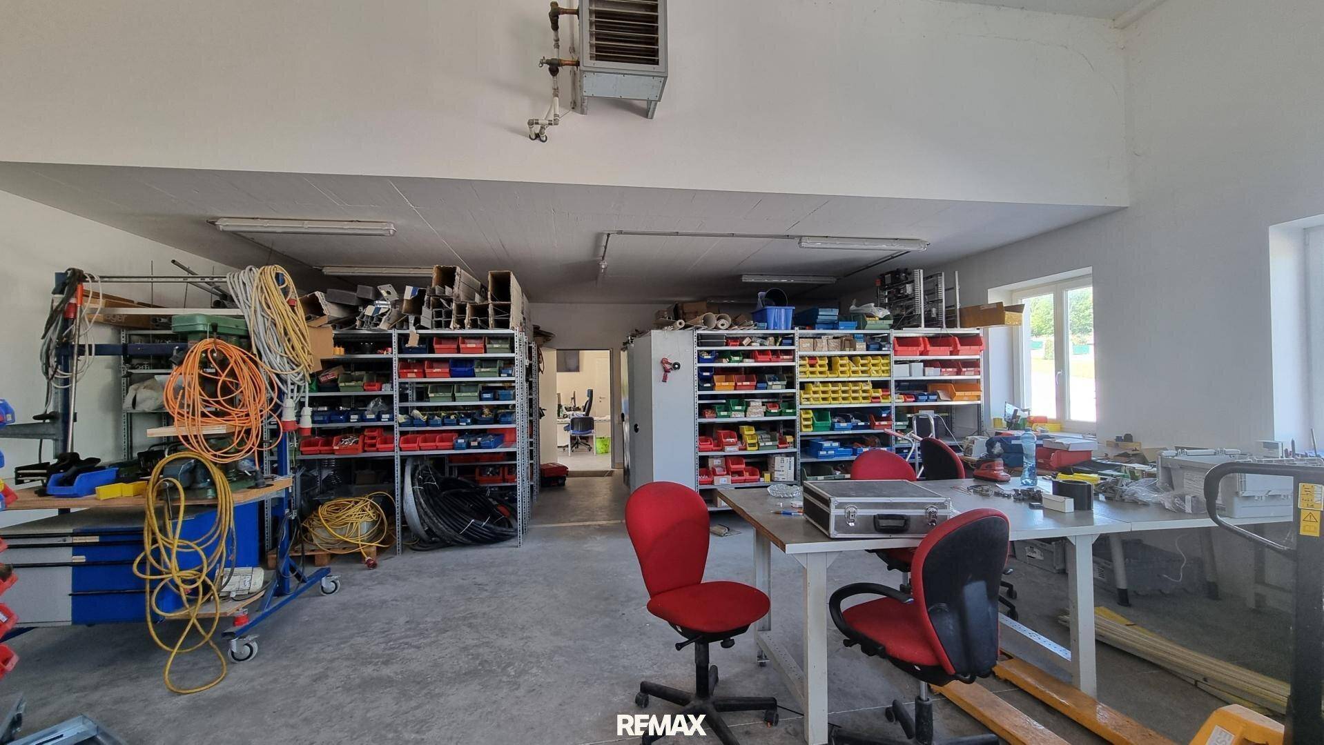 Werkstatt mit Regalen voller Kleinteile, Werkbänken und Fenstern, gut organisiert und hell.