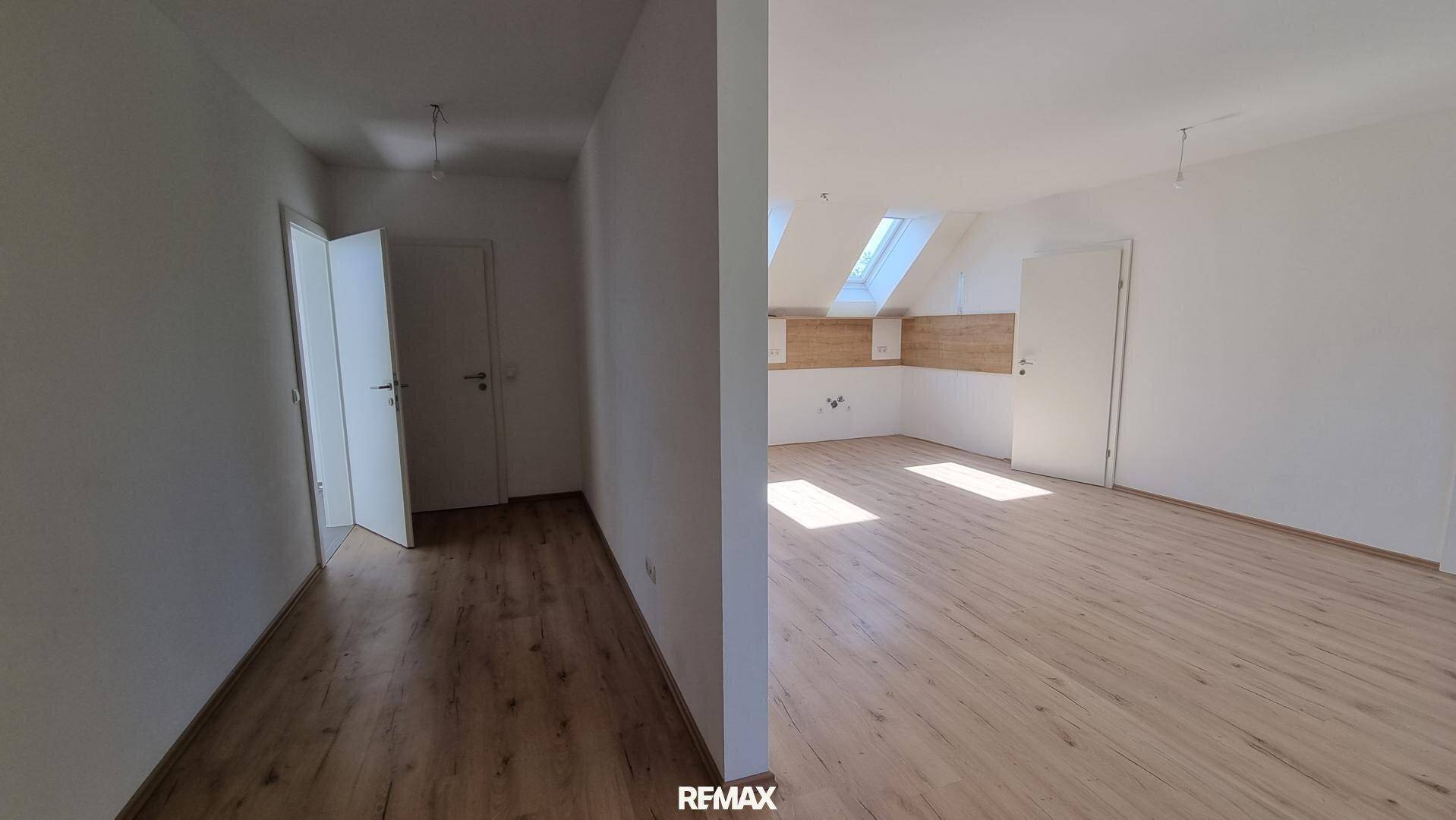 Zwei miteinander verbundene helle Räume mit Laminatboden und Dachfenstern, die viel Tageslicht hereinlassen.