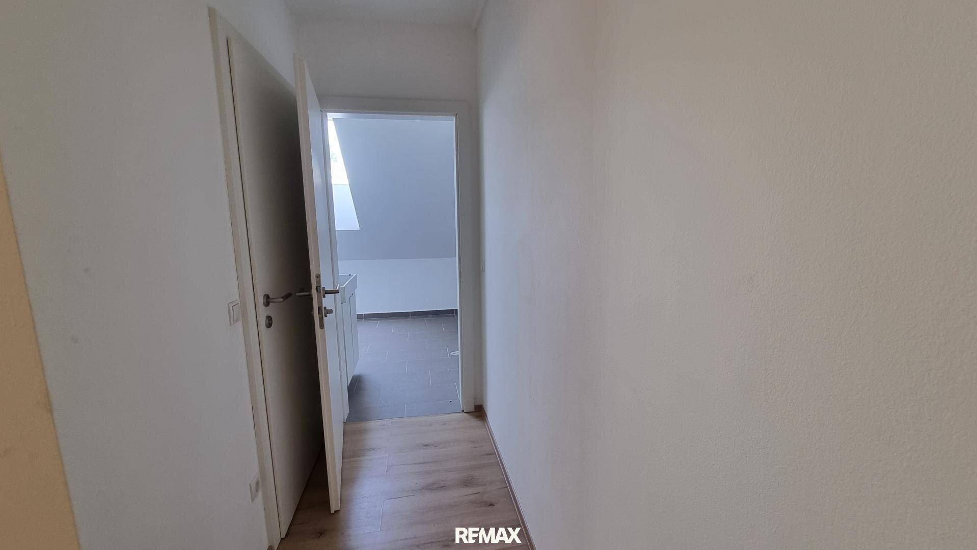 Heller Flur mit Laminatboden und weißen Türen, die zu verschiedenen Räumen führen.