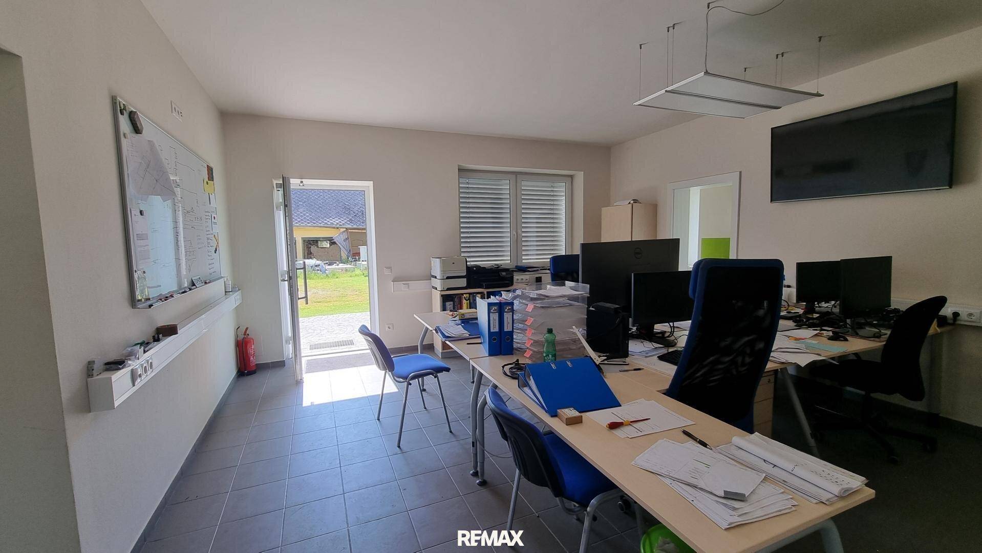 Großes Büro mit mehreren Arbeitsplätzen, Fenstern und Zugang zum Garten, gut beleuchtet.