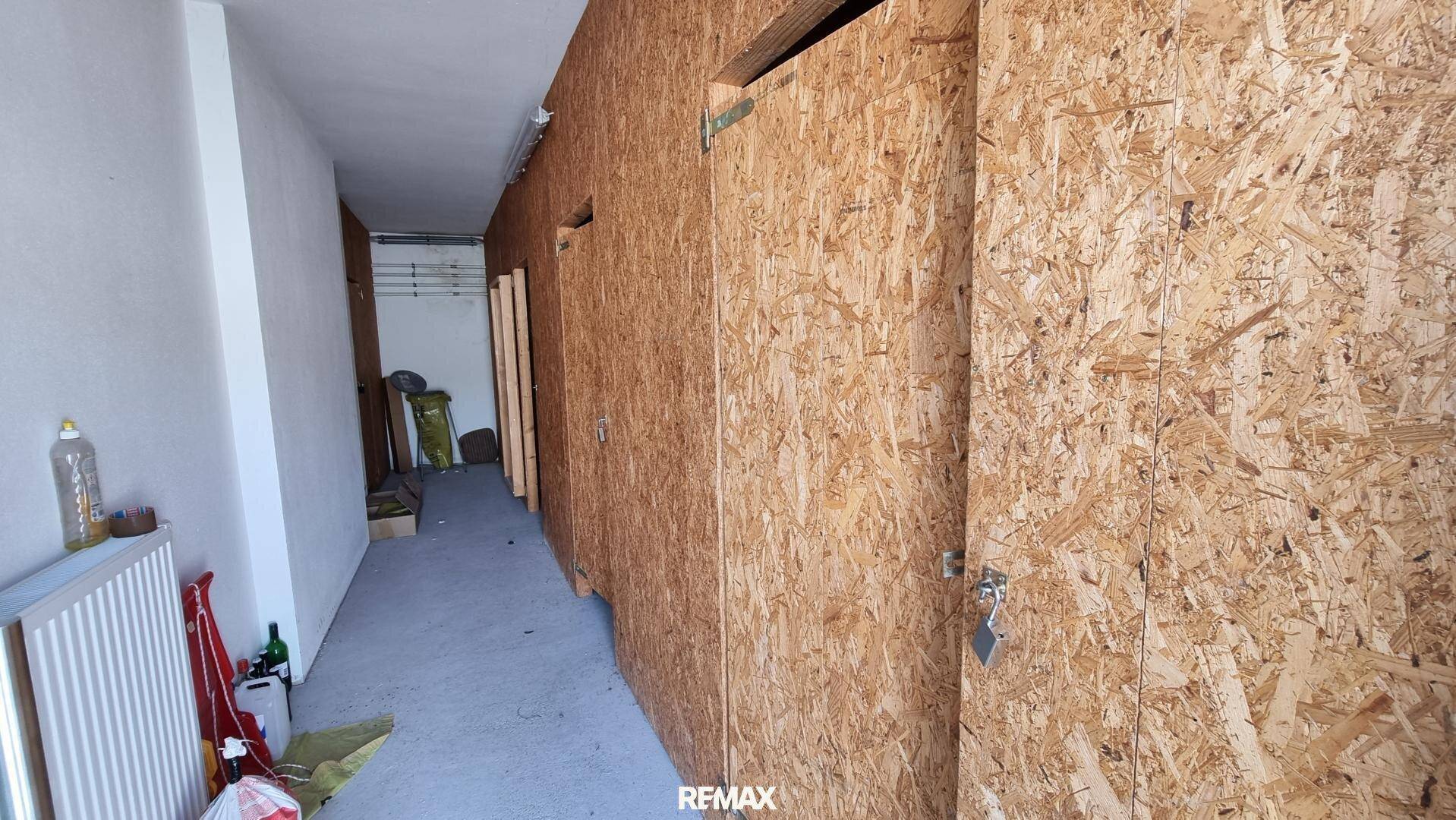 Langer Flur mit OSB-Platten an den Wänden, der zu weiteren Räumen führt, einfacher Ausbau.