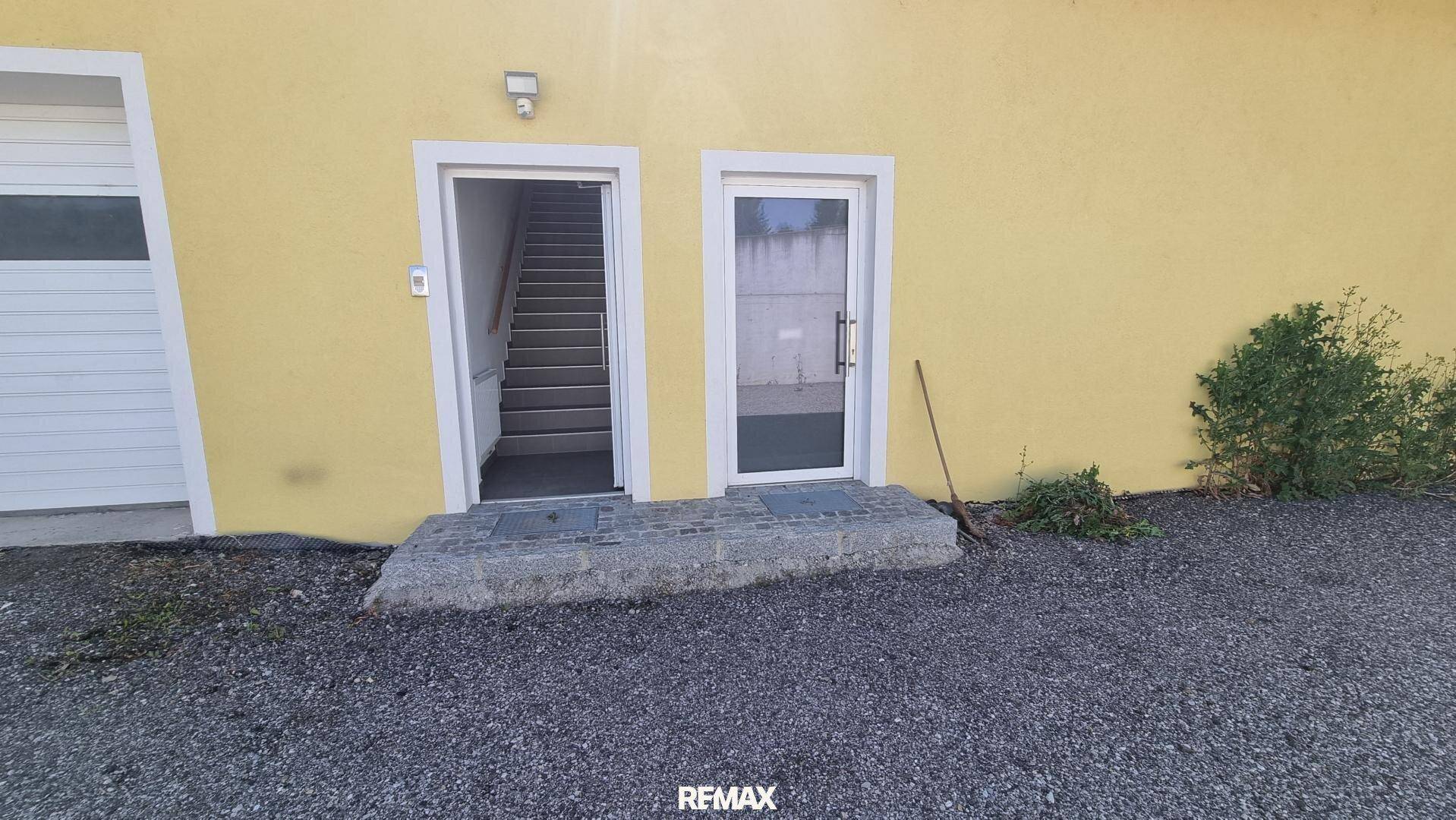 Zwei Eingangstüren an der gelben Fassade, eine davon führt zu einer Treppe im Inneren des Gebäudes.