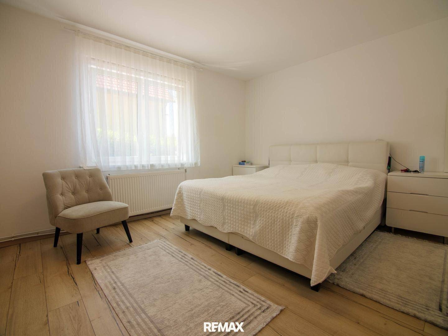 Helles Schlafzimmer mit Doppelbett, Nachttischen und hellem Laminatboden.