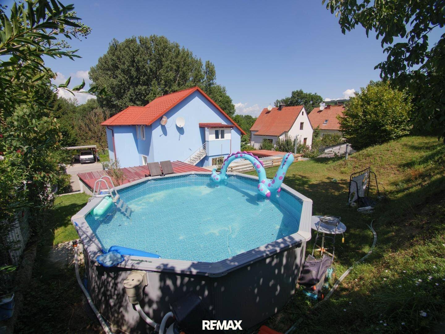 Großer Garten mit Aufstellpool, Liegefläche und Blick auf das Wohnhaus.
