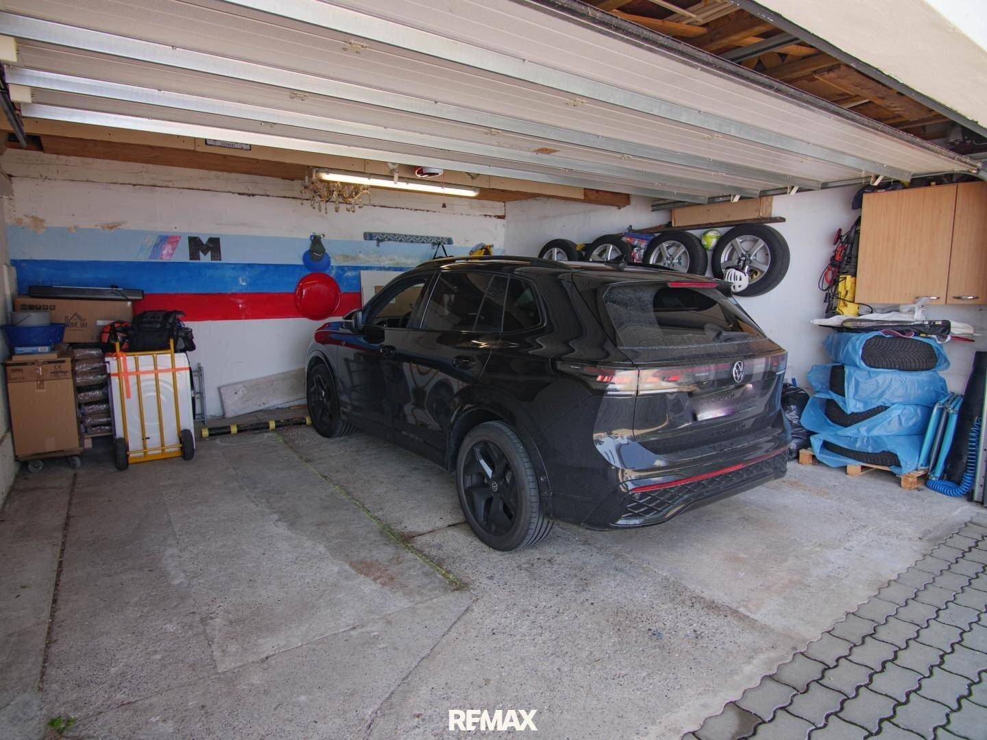 Innenansicht der Garage mit einem geparkten Auto und Stauraum für Reifen und Werkzeuge.