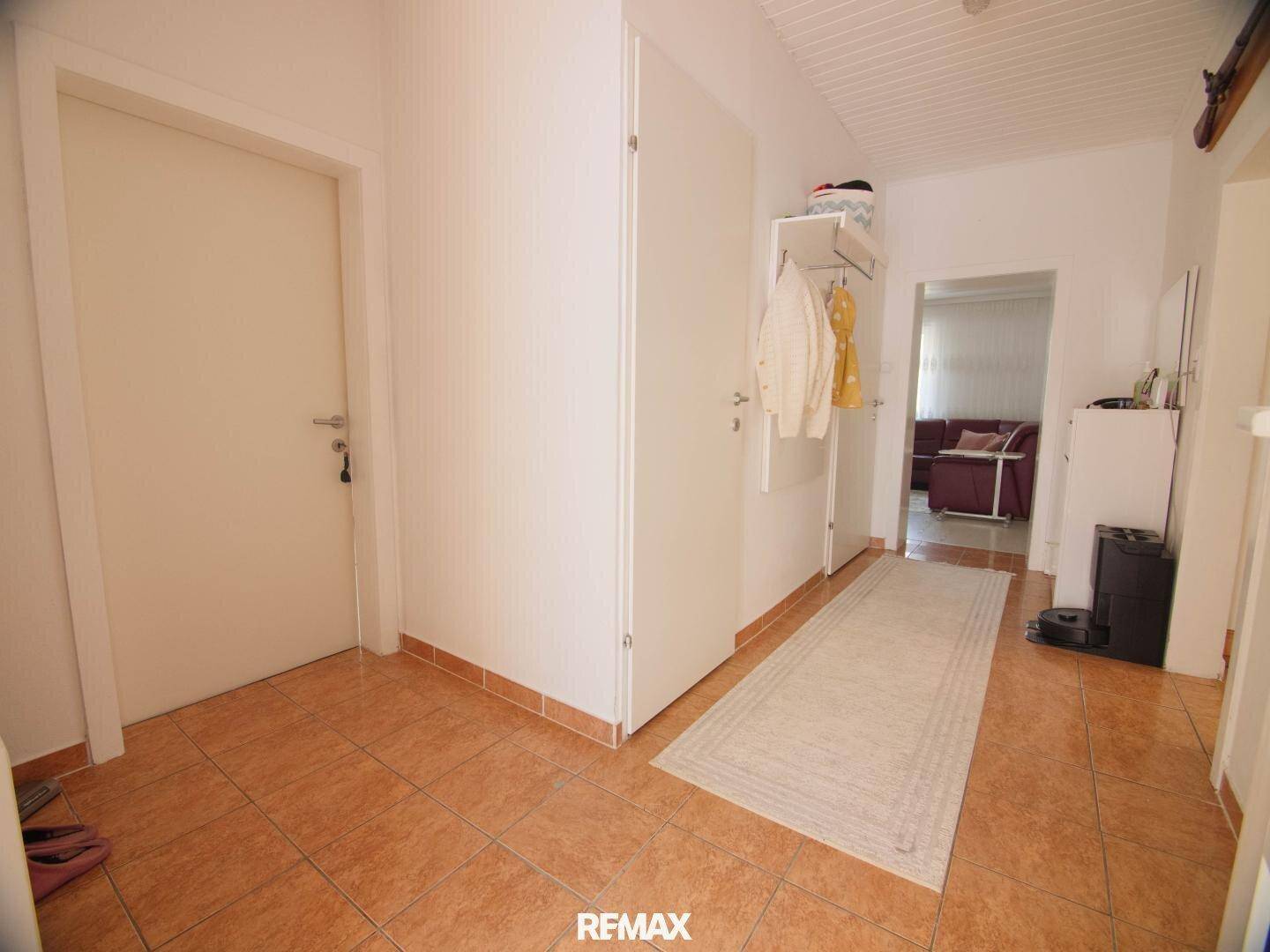 Heller Flur mit Terrakotta-Fliesenboden und Garderobe, führt zu weiteren Räumen.