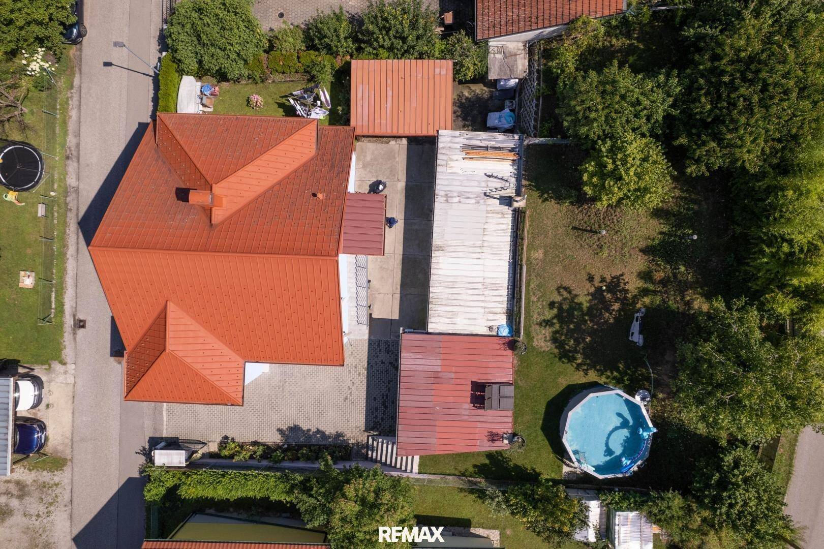Gesamtansicht des Anwesens von oben mit rotem Dach, Terrasse und Poolbereich.