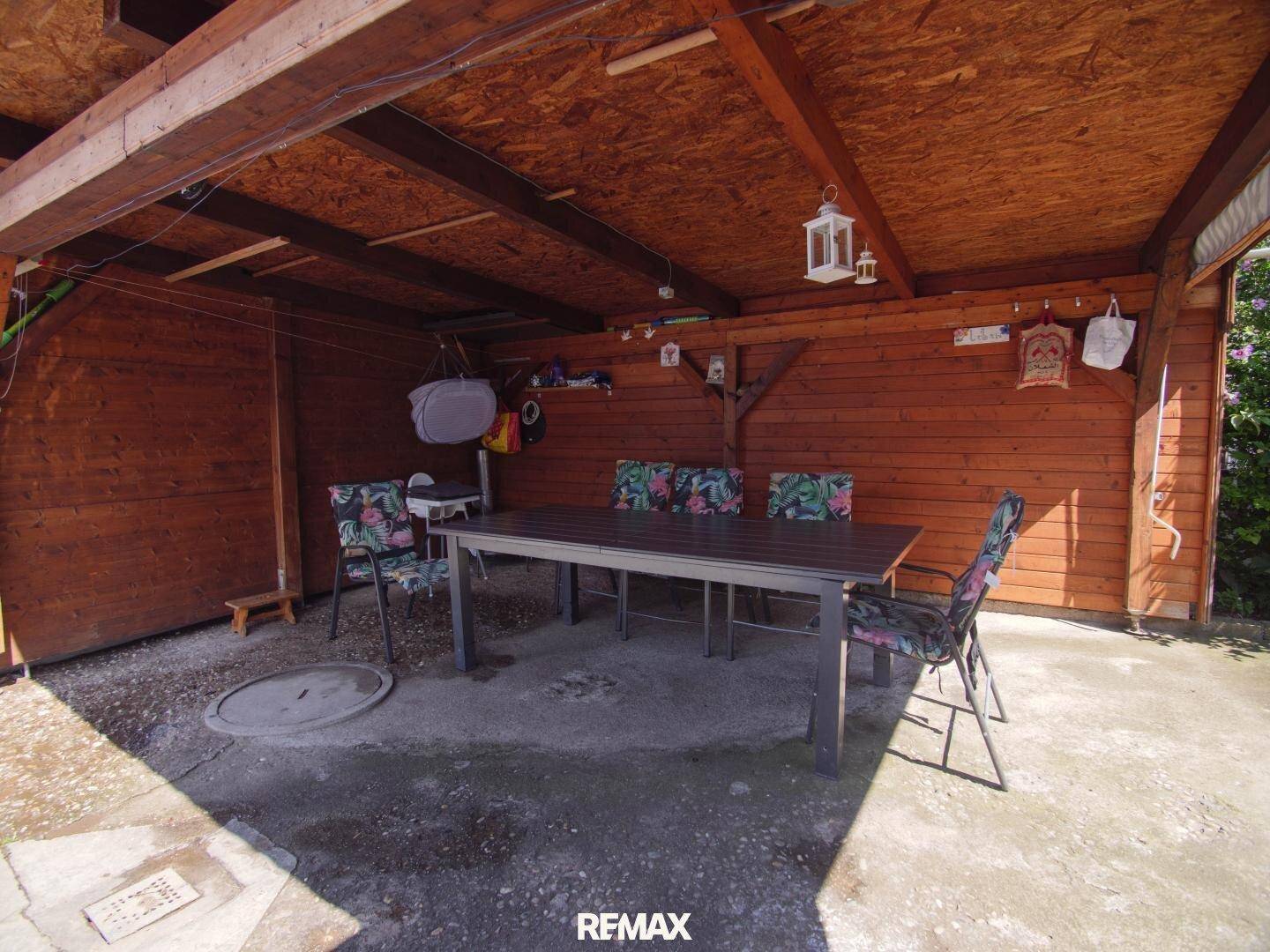 Überdachte Terrasse mit Holzdach und Esstisch, ideal für Mahlzeiten im Freien.