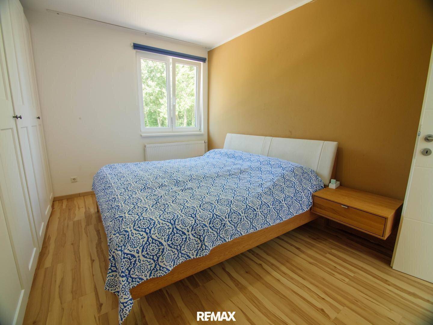 Schlafzimmer mit Doppelbett, Holzboden und einer Akzentwand in Senfgelb.