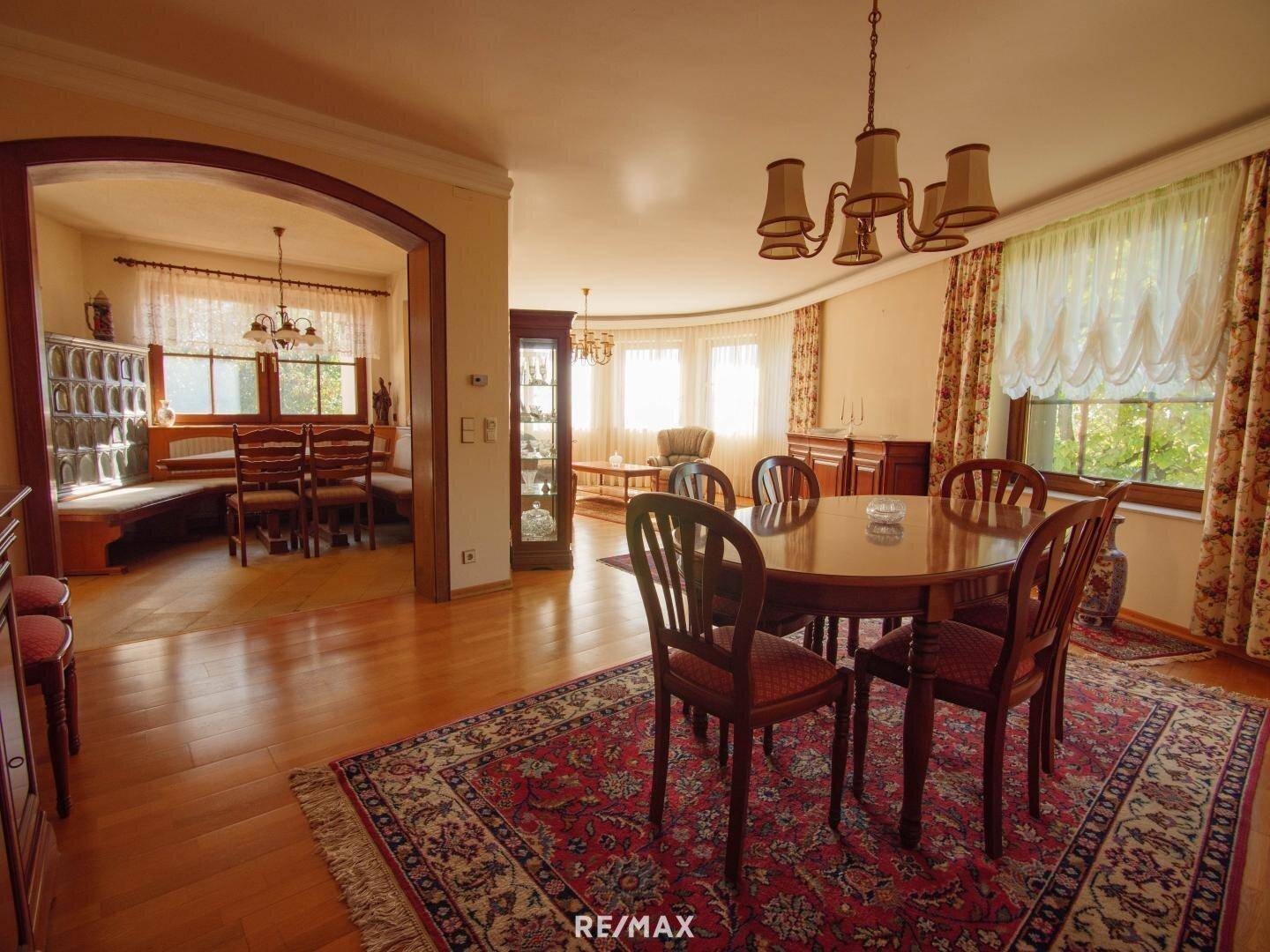 Gemütlicher Wohn-Essbereich mit Holzboden, traditionellen Möbeln und Blick ins Grüne.