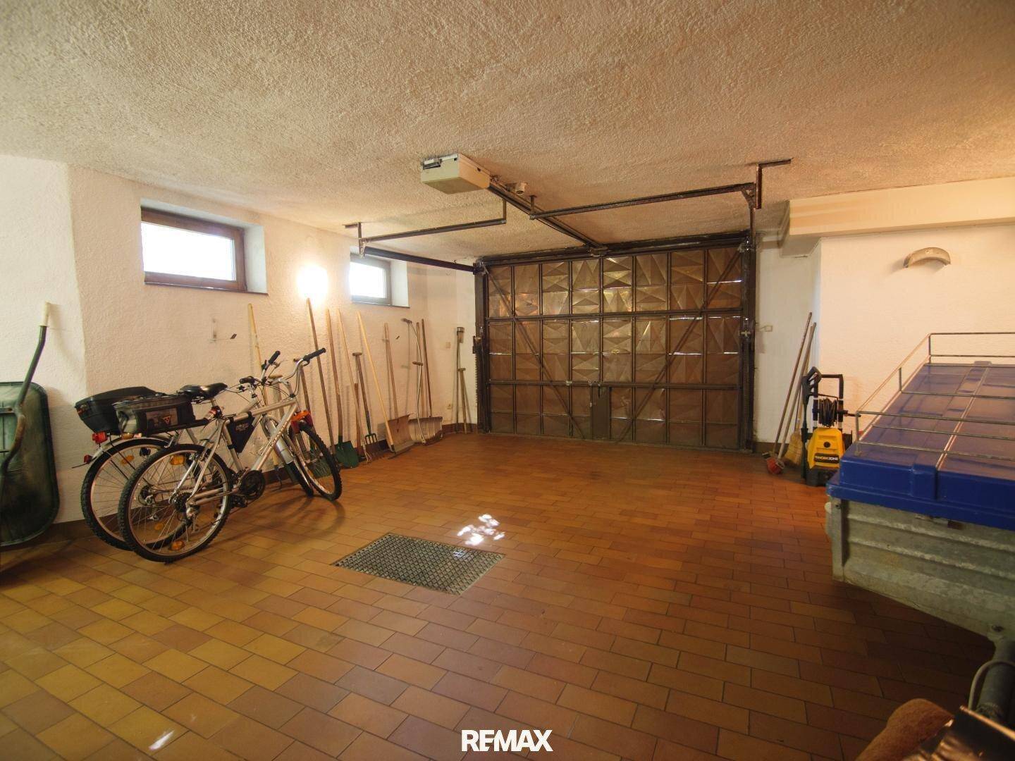 Geräumige Garage mit Platz für Fahrzeuge und Fahrräder, ausgestattet mit einem Garagentor.