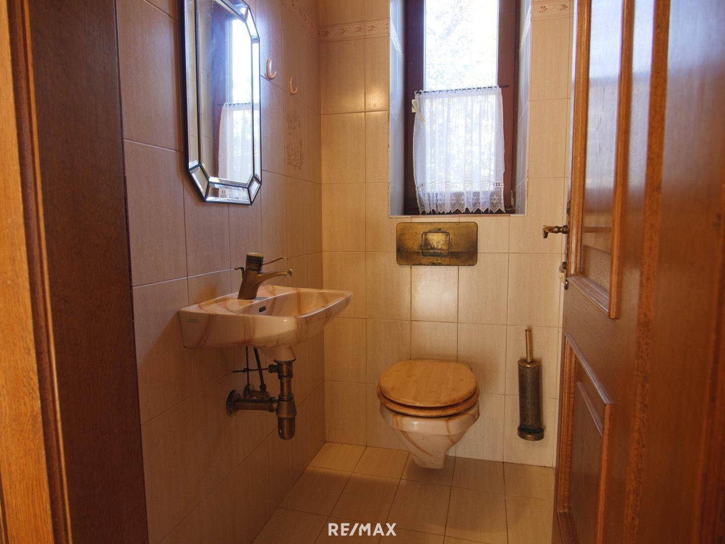 Kleines Gäste-WC mit Fenster, Fliesen und traditionellem Holzwaschtisch.