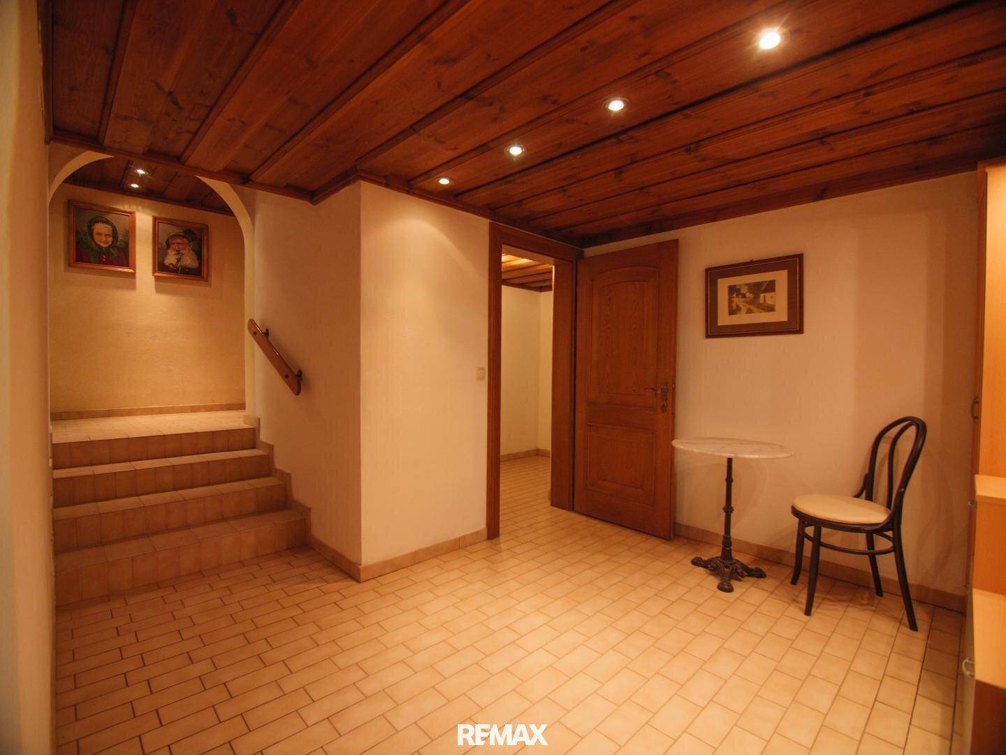 Flur im Untergeschoss mit Fliesenboden, Holzdecke und Treppe nach oben.