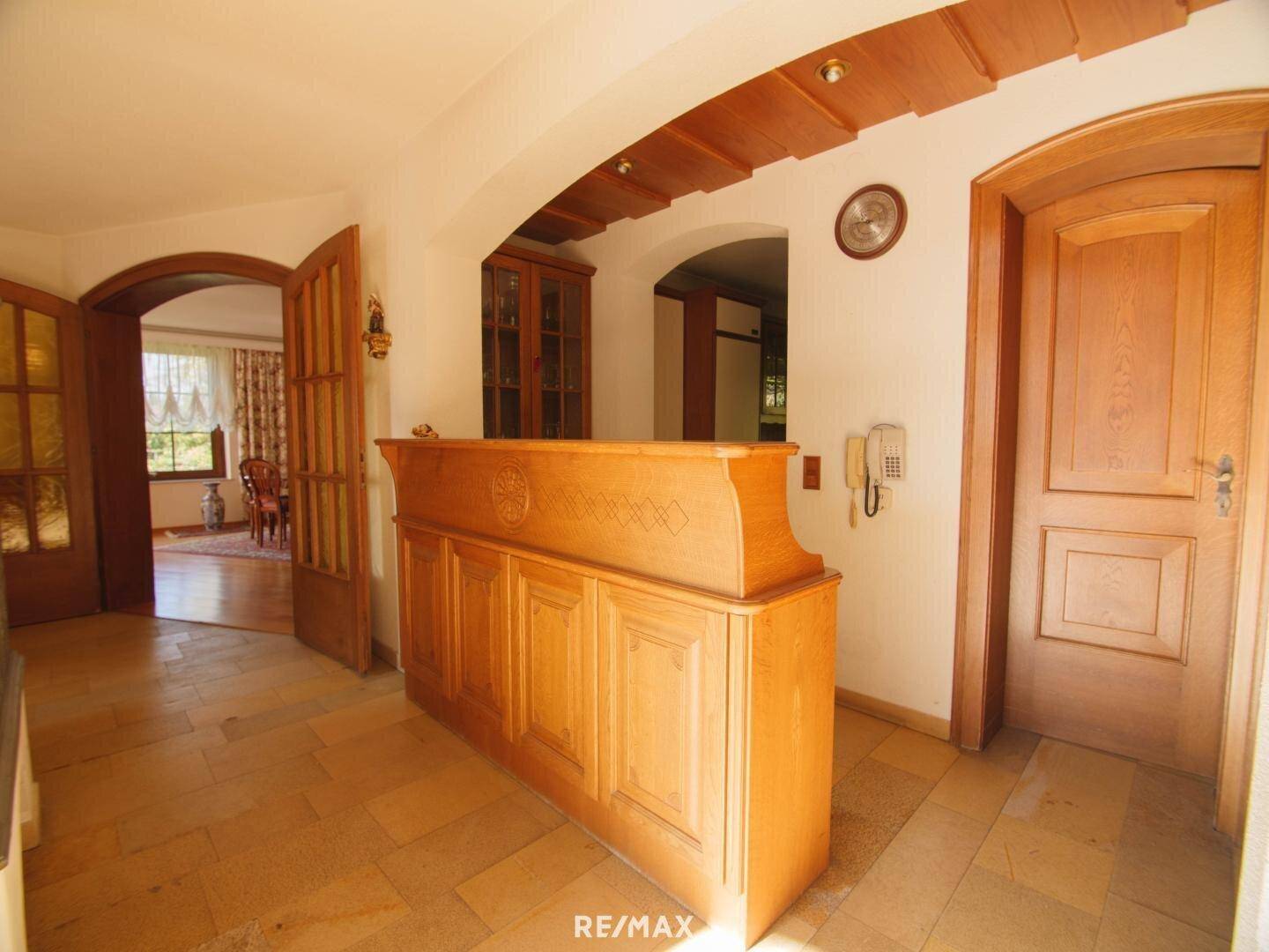 Eingangsbereich mit gefliestem Boden, Holztüren und einer traditionellen Holztheke.