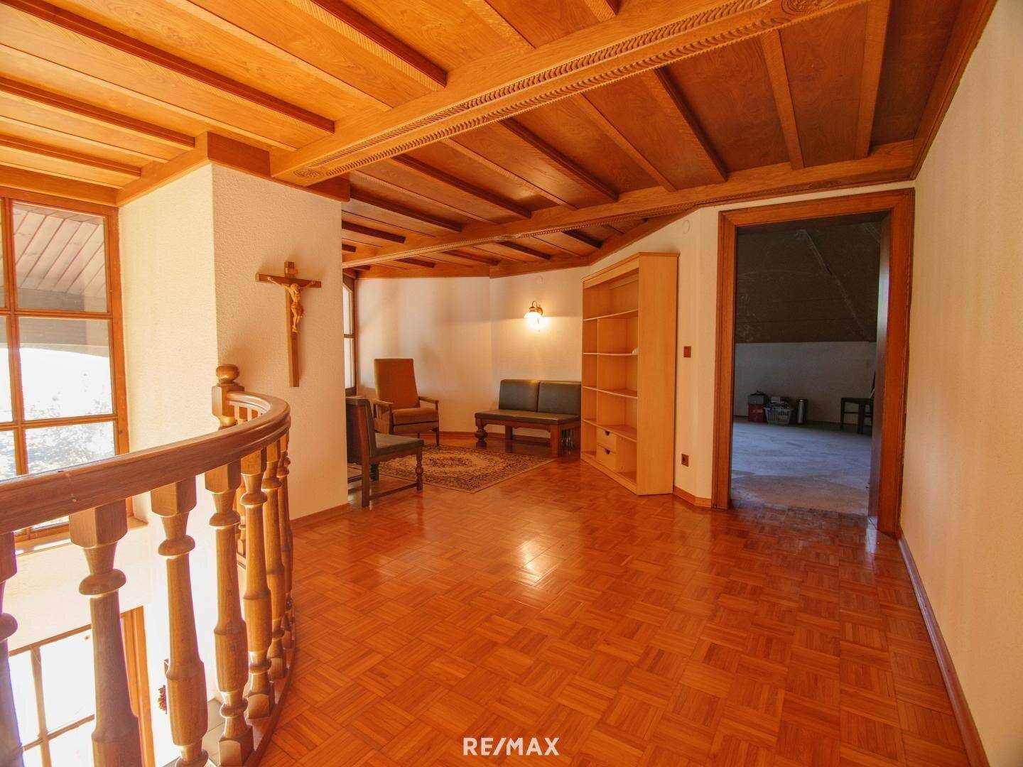 Heller Flur im Obergeschoss mit Holzboden, Holzdecke und Blick nach draußen.