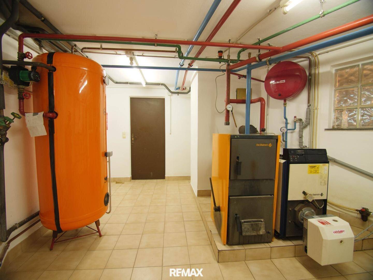 Heizungsraum im Keller mit großem Warmwasserspeicher und komplexer Rohrinstallation.