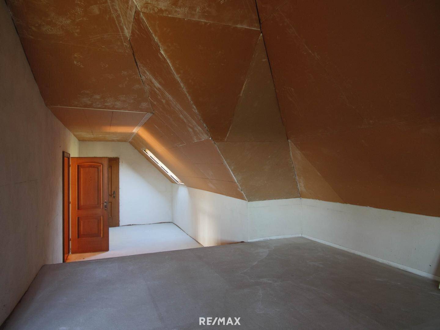 Unausgebauter Dachboden mit schrägen Wänden, Dachfenstern und Holztüren.