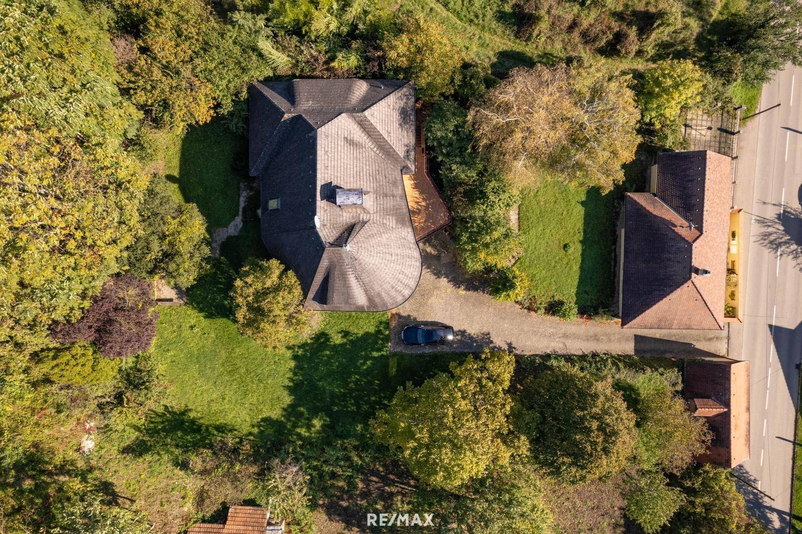 Senkrechte Luftaufnahme des Hauses mit geschwungenem Dach und umliegendem Grundstück.