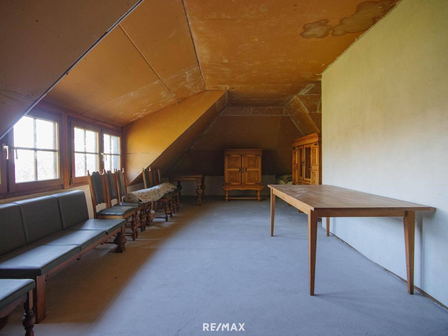 Geräumiger Dachboden mit schrägen Wänden, Fenstern und Holzbänken.