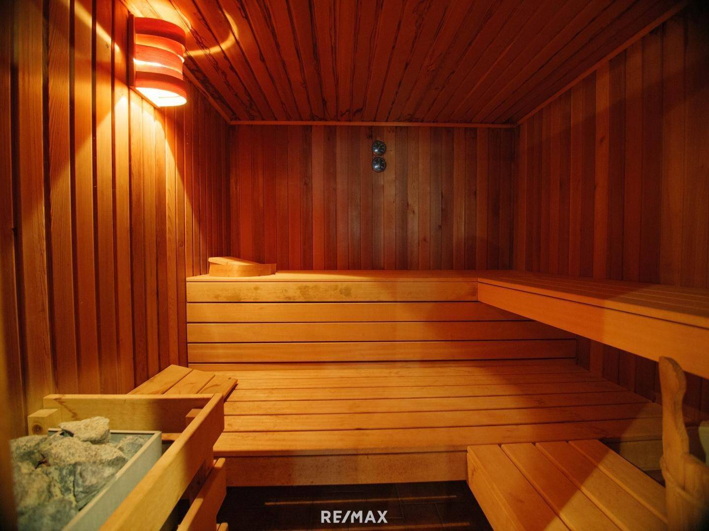 Innenansicht einer traditionellen Holzsauna mit Bänken und Heizofen.