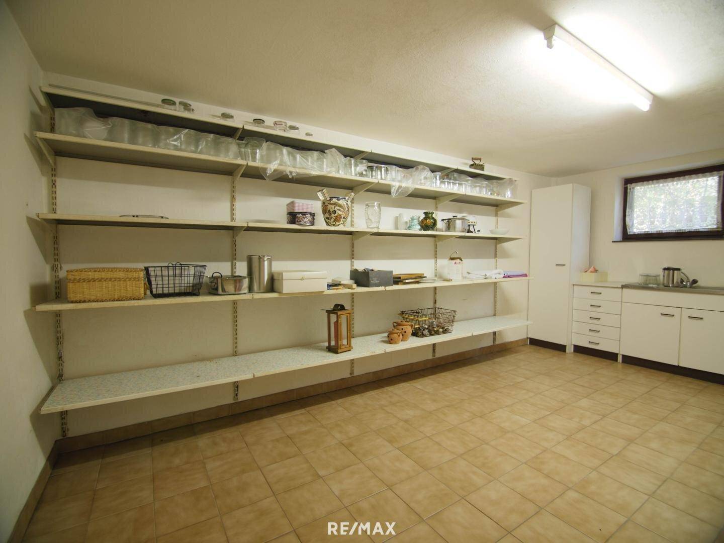 Großer Abstellraum im Keller mit Regalen, Spüle und Fenster.